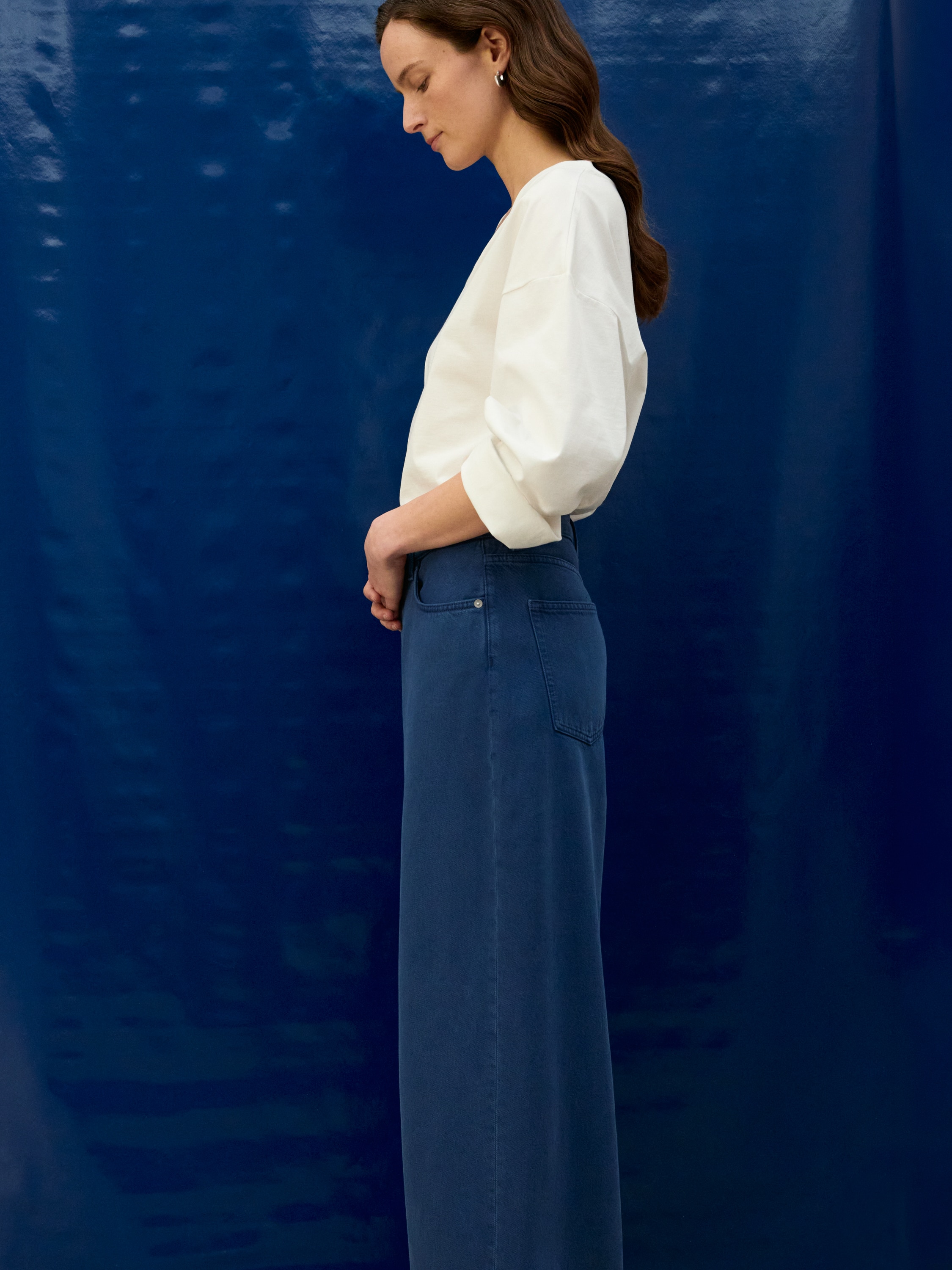 Les jeans larges surdimensionnés CEDAR sont de couleur bleu moyen, arborant une silhouette à jambes larges surdimensionnées, et sont présentés de face. Ils affichent un style à cinq poches avec des poches avant et une poche à monnaie, ainsi qu'une fermeture visible à boutons et à glissière à la taille.
