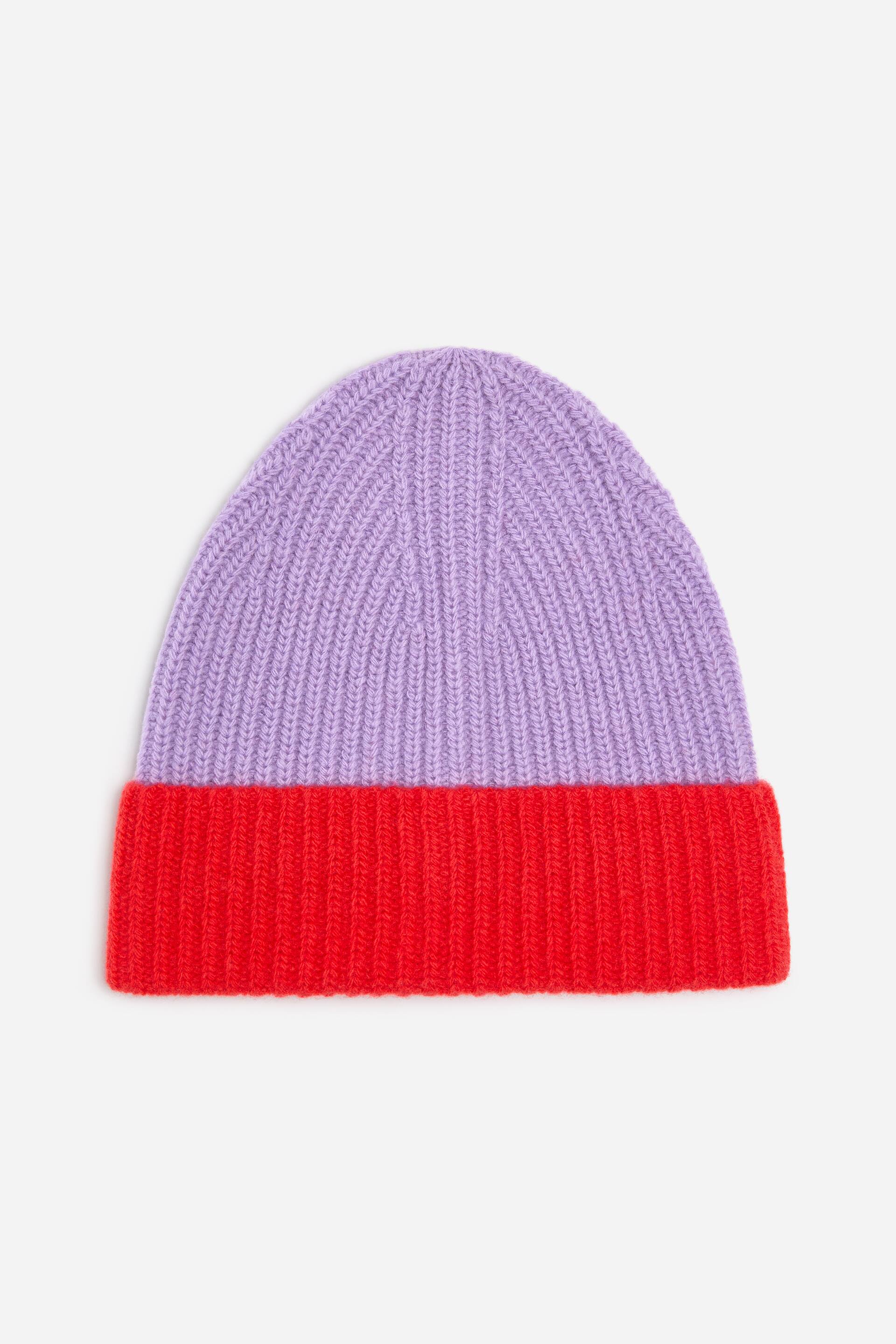 Se større billede: En tofarvet beanie-hat viser en lys lilla øverste del og en klar rød ombukket kant, alt sammen med en ribstrikket tekstur.