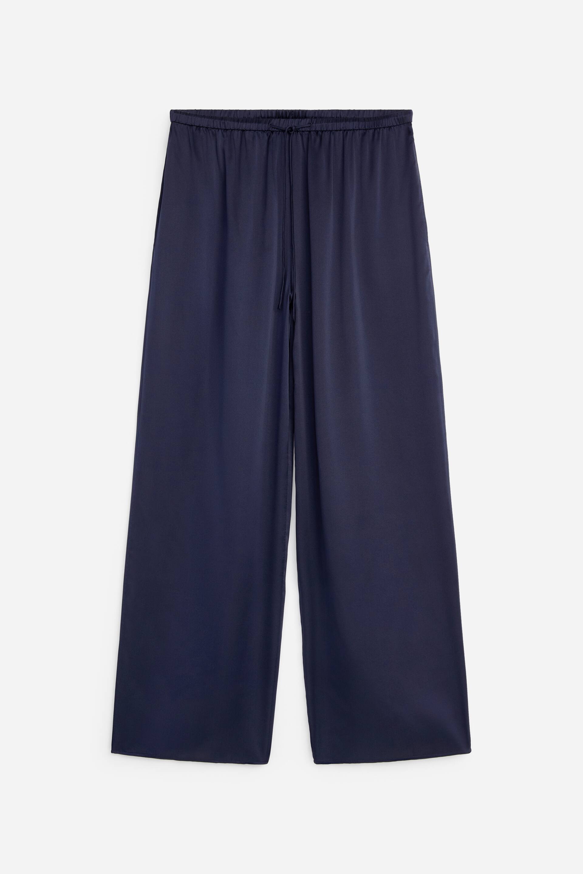Ver imagen más grande: Los pantalones de color azul oscuro, con forma de globo, se presentan desde el frente. Están confeccionados en satén de seda fluida y cuentan con una cintura elástica con cordones visibles y discretos bolsillos en las costuras laterales.