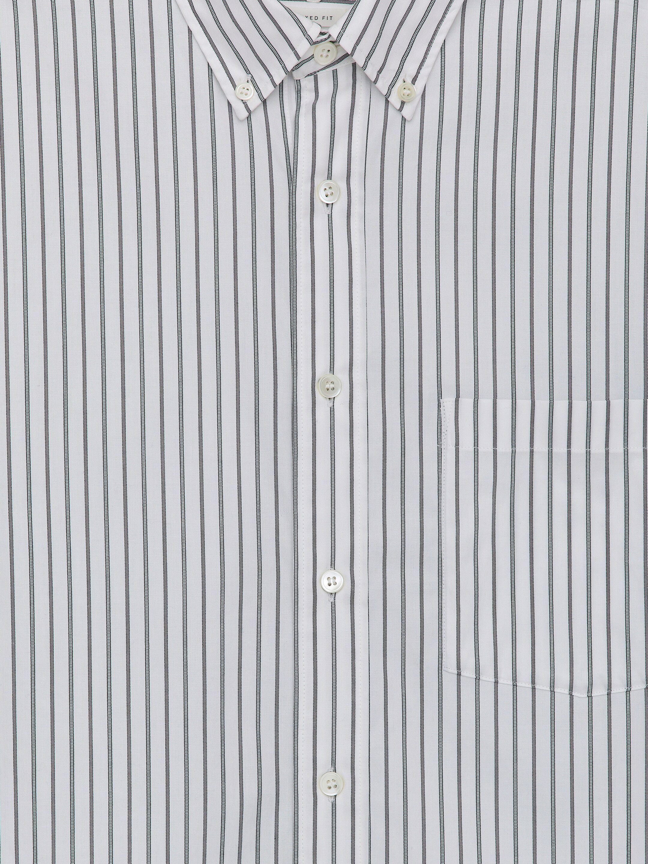 Visualizza immagine più grande: Una camicia bianca con sottili righe verticali scure è mostrata dal davanti. Presenta un colletto con punte abbottonate, un cannoncino centrale con bottoni in madreperla e una tasca applicata singola sul petto sinistro.