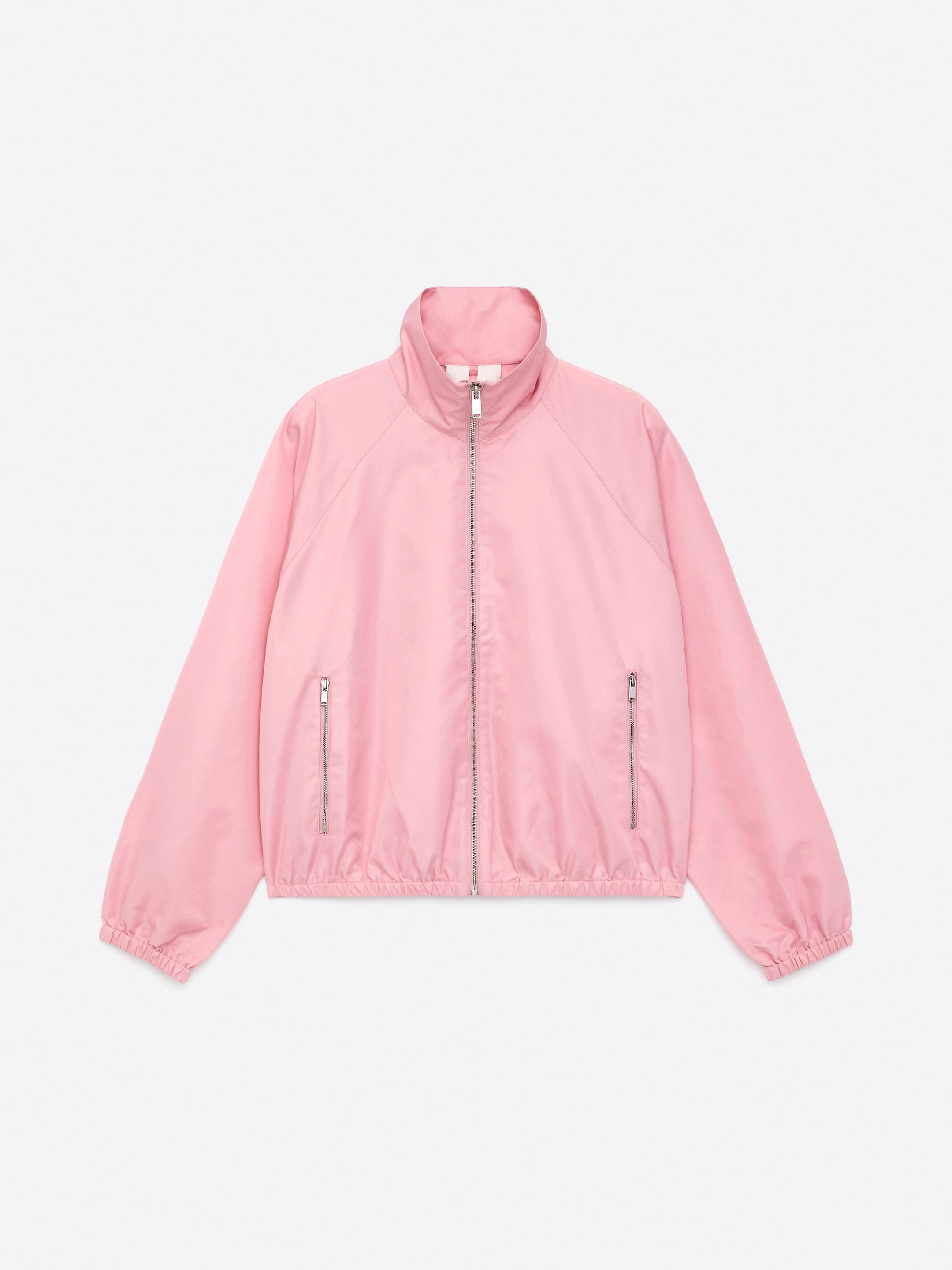 Vis større bilde: En sporty rosa nylonjakke presenteres forfra, med en full-lengde metallglidelås nedover midten og to vertikale metallglidelåslommer på nedre front. Den er designet med en stående krage, og elastiske mansjetter og nederkant.