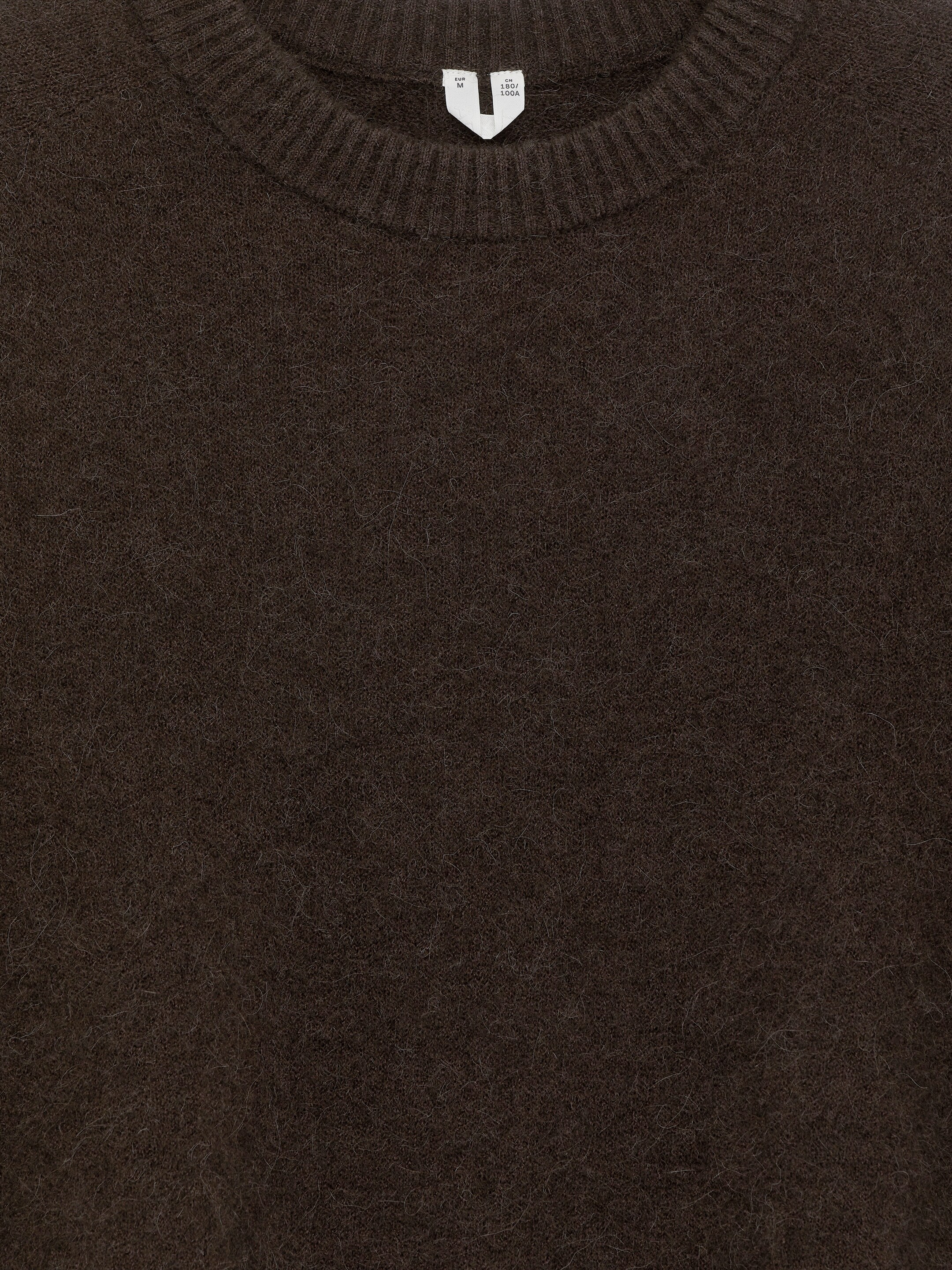 Größeres Bild anzeigen: Ein dunkelbrauner, grob gestrickter Pullover mit Rundhalsausschnitt wird von vorne gezeigt. Er zeichnet sich durch eine sichtbar haarige Oberfläche und einen gerippten Rundhalsausschnitt aus.