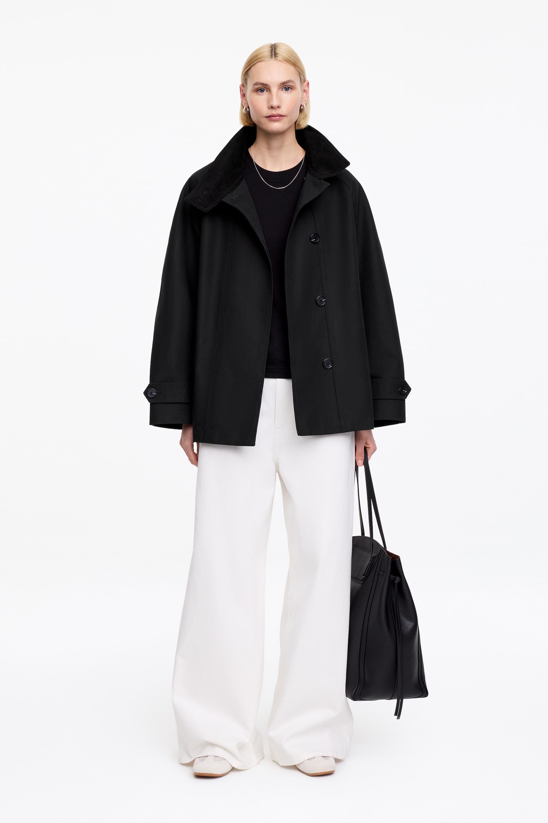 View larger image: A black jacket featuring a contrasting dark textured standing collar and a button-front fastening with black buttons. It is designed with long sleeves ending in adjustable button tabs at the cuffs, showcasing its relaxed, hip-length fit.