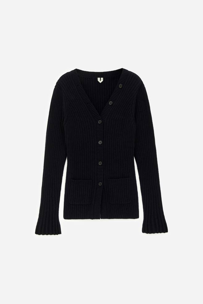 A black ribbed knit cardigan is being displayed from the front, featuring a V-neckline, a seven-button front closure, long sleeves with flared ribbed cuffs, and two front patch pockets. - 1