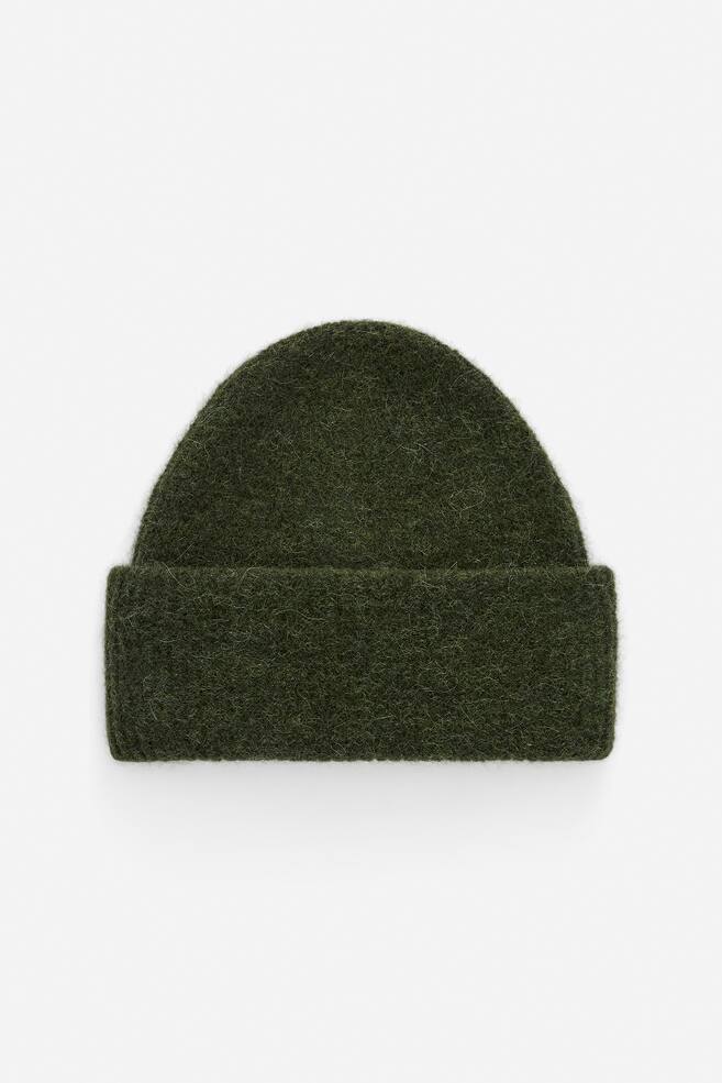 A dark green chunky rib-knit beanie is being presented from the FRONT, displaying a fuzzy texture, a fitted shape, and a wide brim that is folded up. - 1