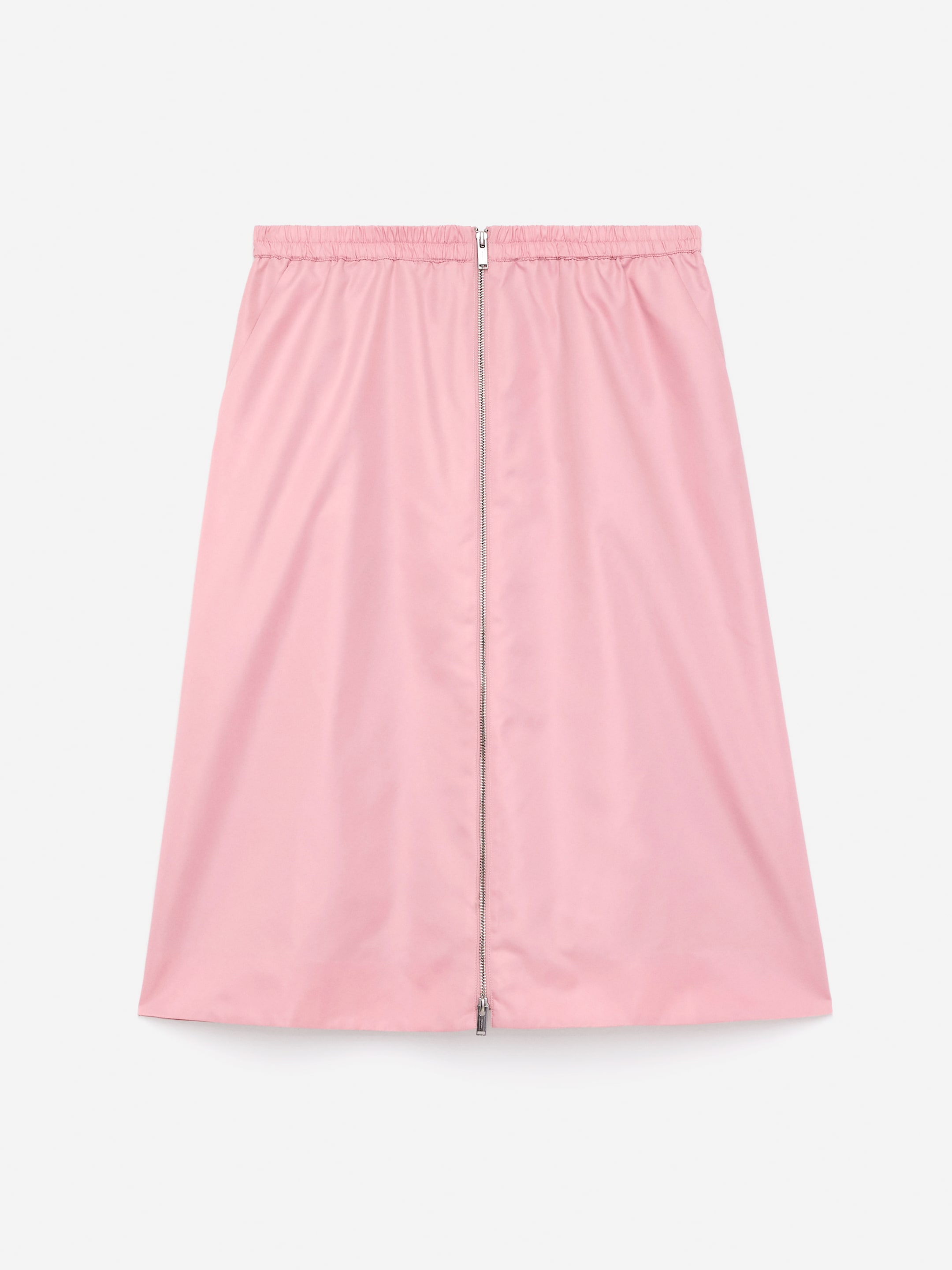 View larger image: A pink midi skirt is being presented from the front. It is featuring an elasticated waist, a two-way metallic zip running down the center front, and subtle side pockets.