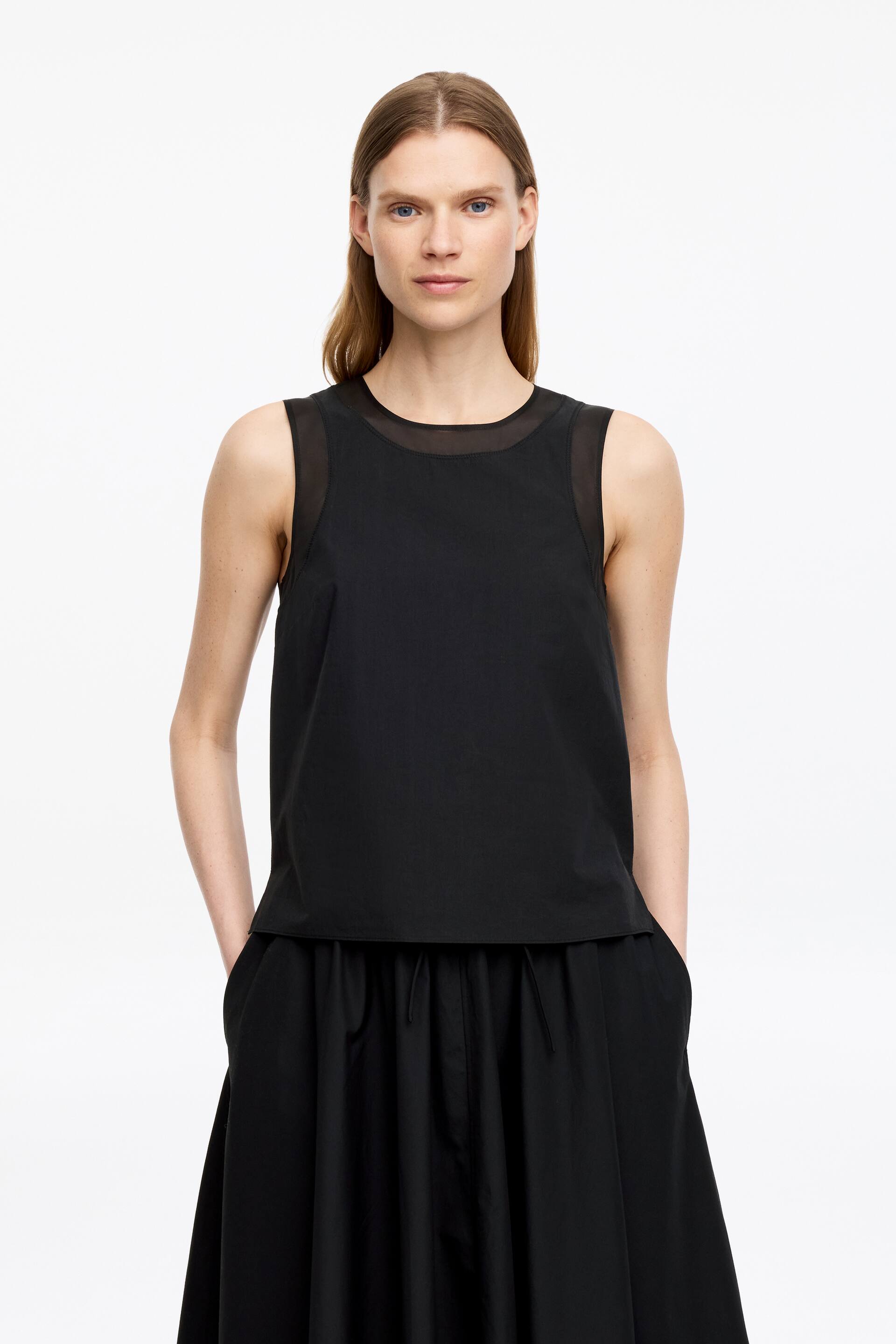Grotere afbeelding bekijken: Een zwarte mouwloze top met een transparante mesh inzet en een ronde halslijn, gestyled met een bijpassende zwarte volle rok met een geplooide trekkoord taille en zijzakken.