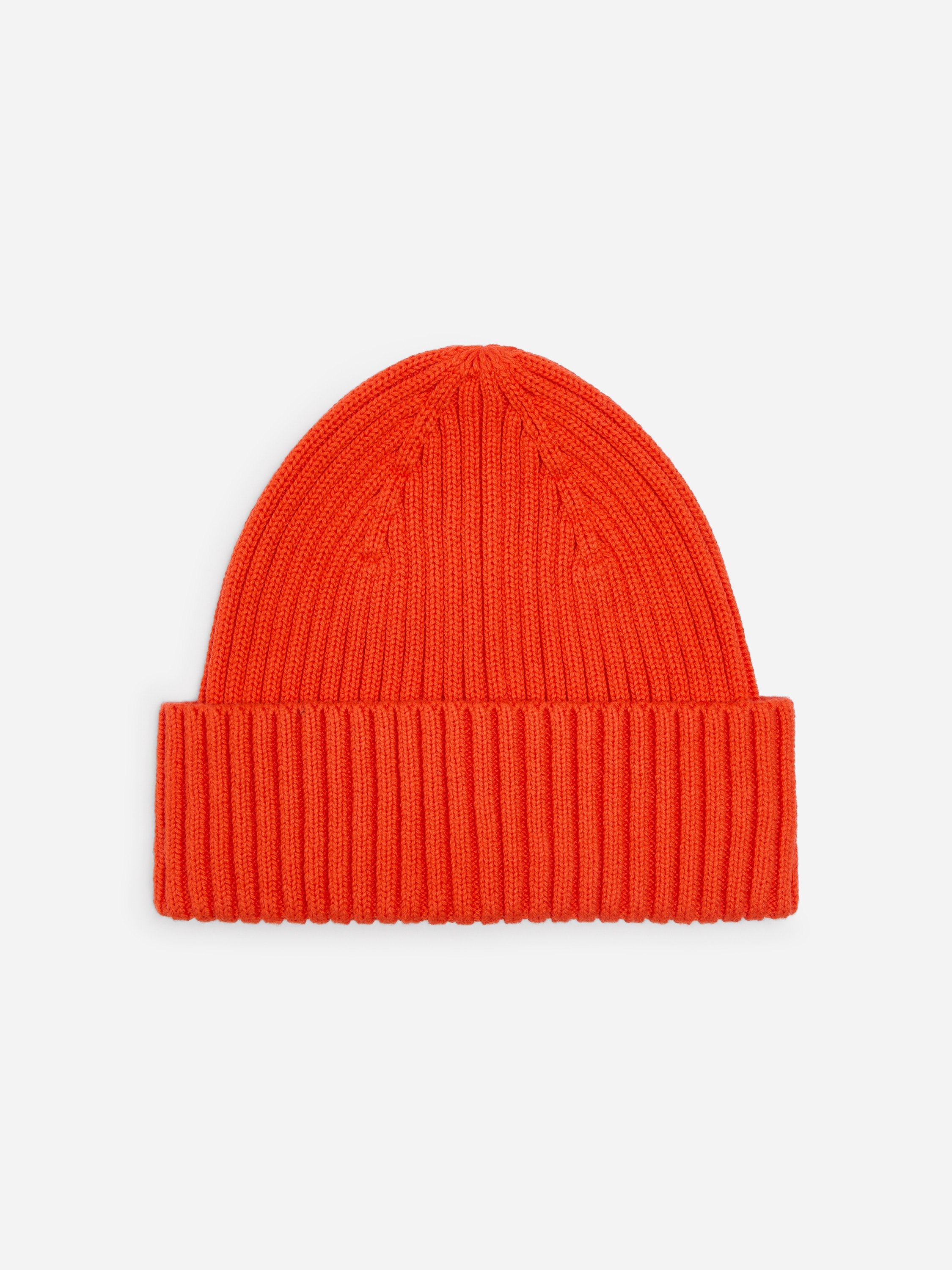 Un bonnet en tricot rouge couvre la tête, présentant un motif en maille côtelée.