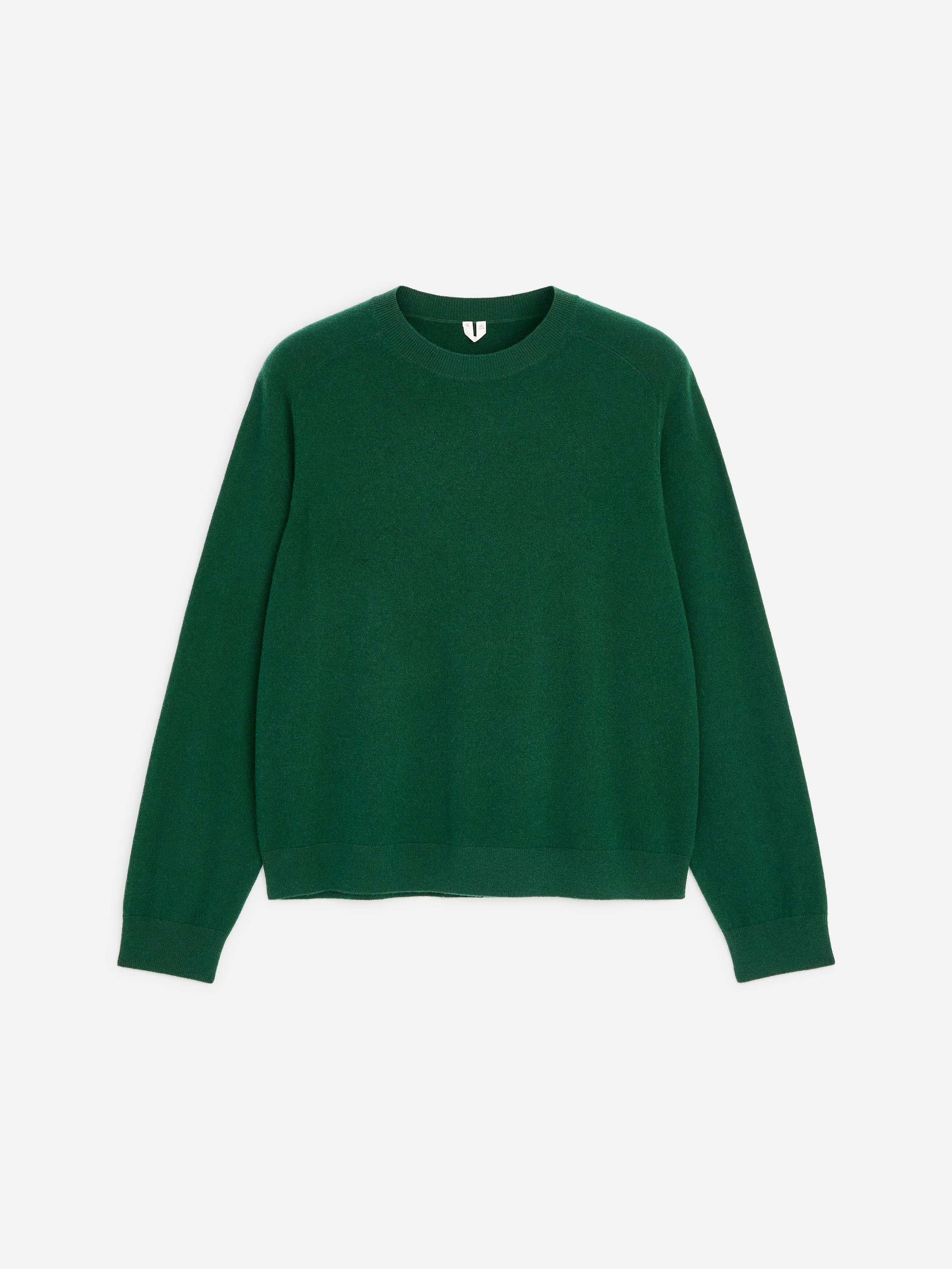 La modella indossa un maglione girocollo verde, in maglia fine, che mette in risalto una vestibilitÃ  regolare con bordi a coste sullo scollo e sui polsini. Il maglione Ã¨ leggermente infilato in vita in jeans denim scuro.
