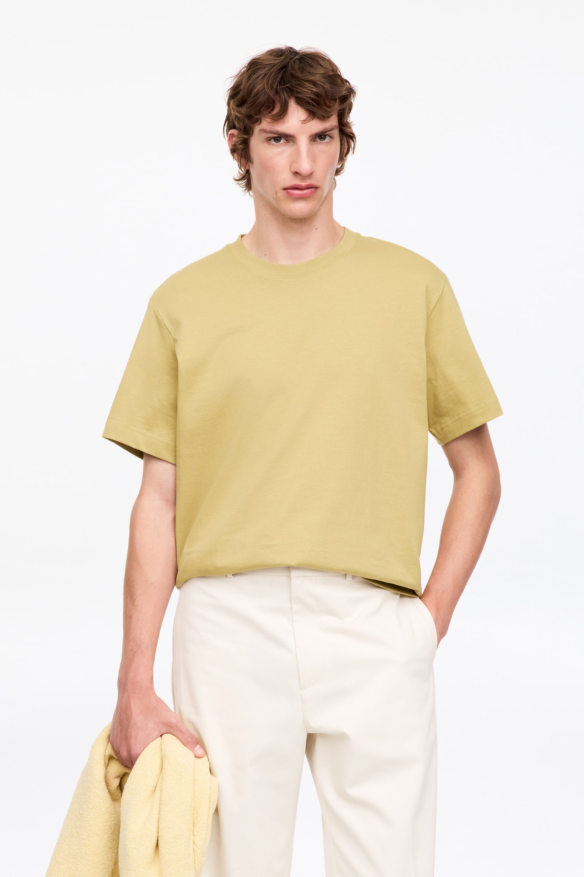Visualizza immagine più grande: Una t-shirt verde giallo pallido presenta un girocollo e maniche corte, mostrando una vestibilità rilassata sul davanti.