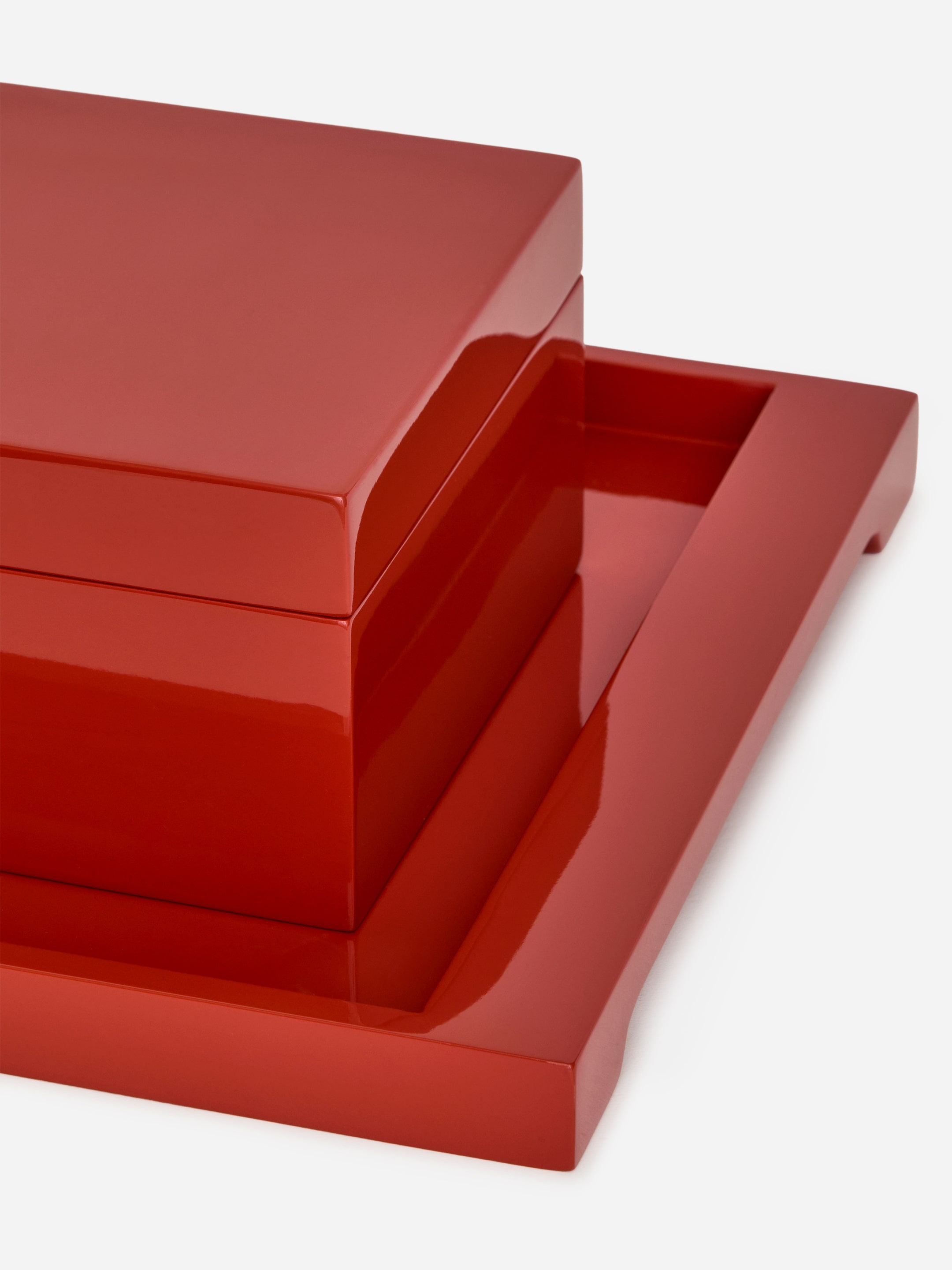 Visualizza immagine più grande: Una scatola quadrata, caratterizzata da una finitura in lacca lucida di un rosso intenso, è posizionata su un vassoio rettangolare coordinato. Il coperchio della scatola è chiuso e il vassoio presenta un bordo rialzato a forma di U che delimita la scatola sul retro e sul lato destro.