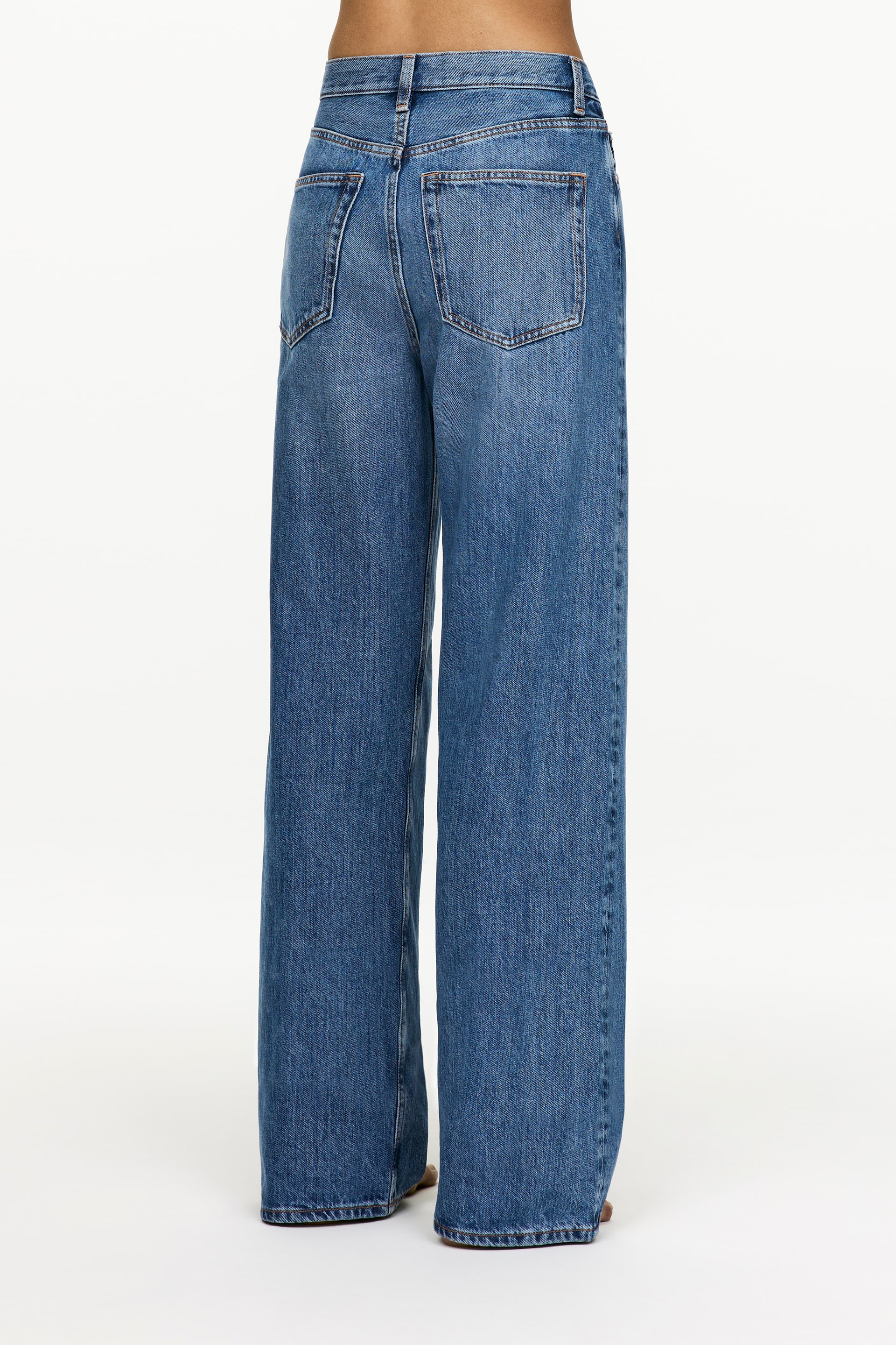 Visa större bild: Blå denimjeans presenteras bakifrån, med hög midja och vida ben, och visar två bakfickor, bälteshällor och okstickningar.