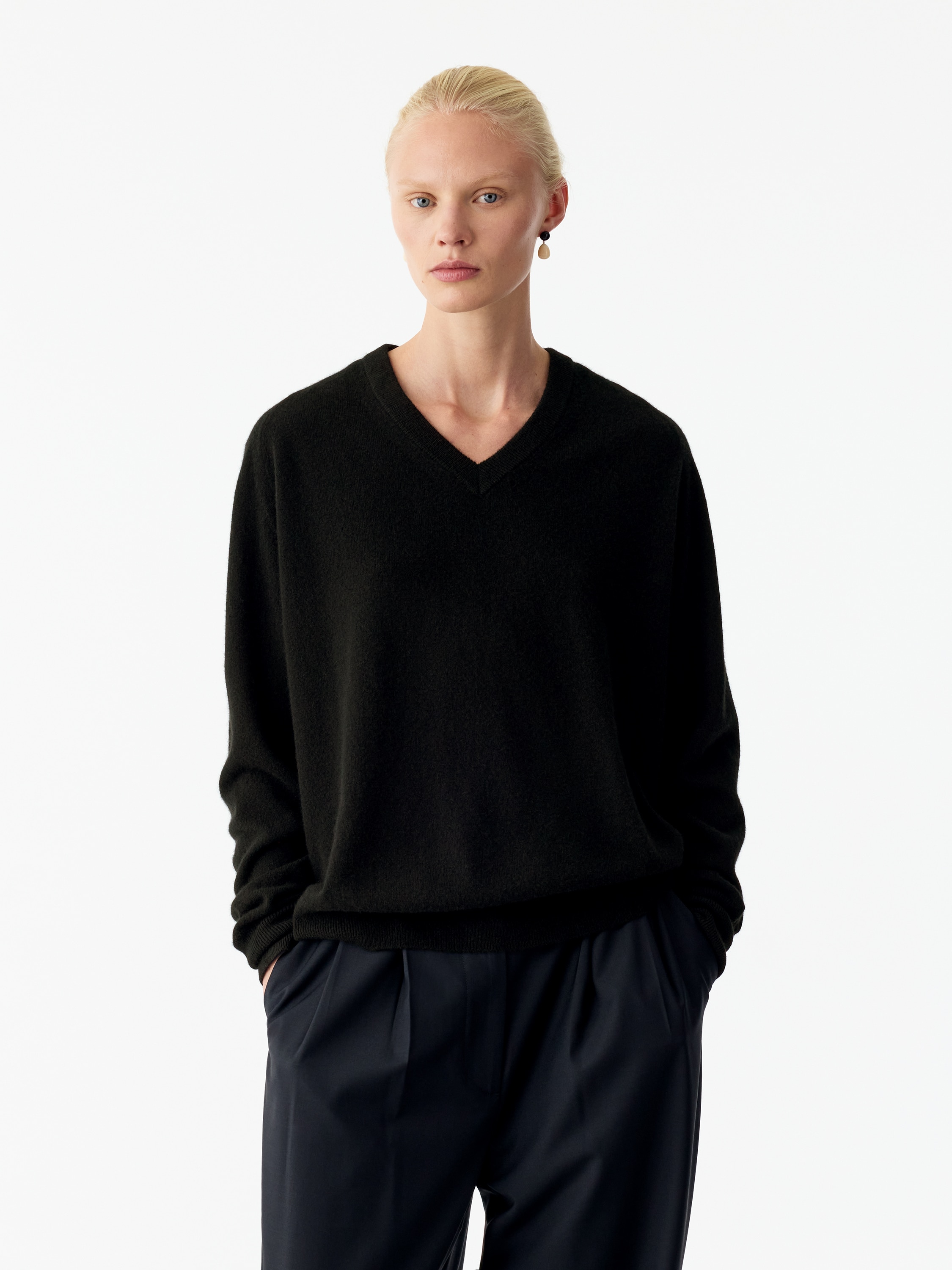 Un maglione nero Relaxed Cashmere con scollo a V Ã¨ mostrato frontalmente, caratterizzato da una silhouette rilassata, da uno scollo a V a coste e da maniche lunghe con polsini a coste e un orlo a coste coordinato.