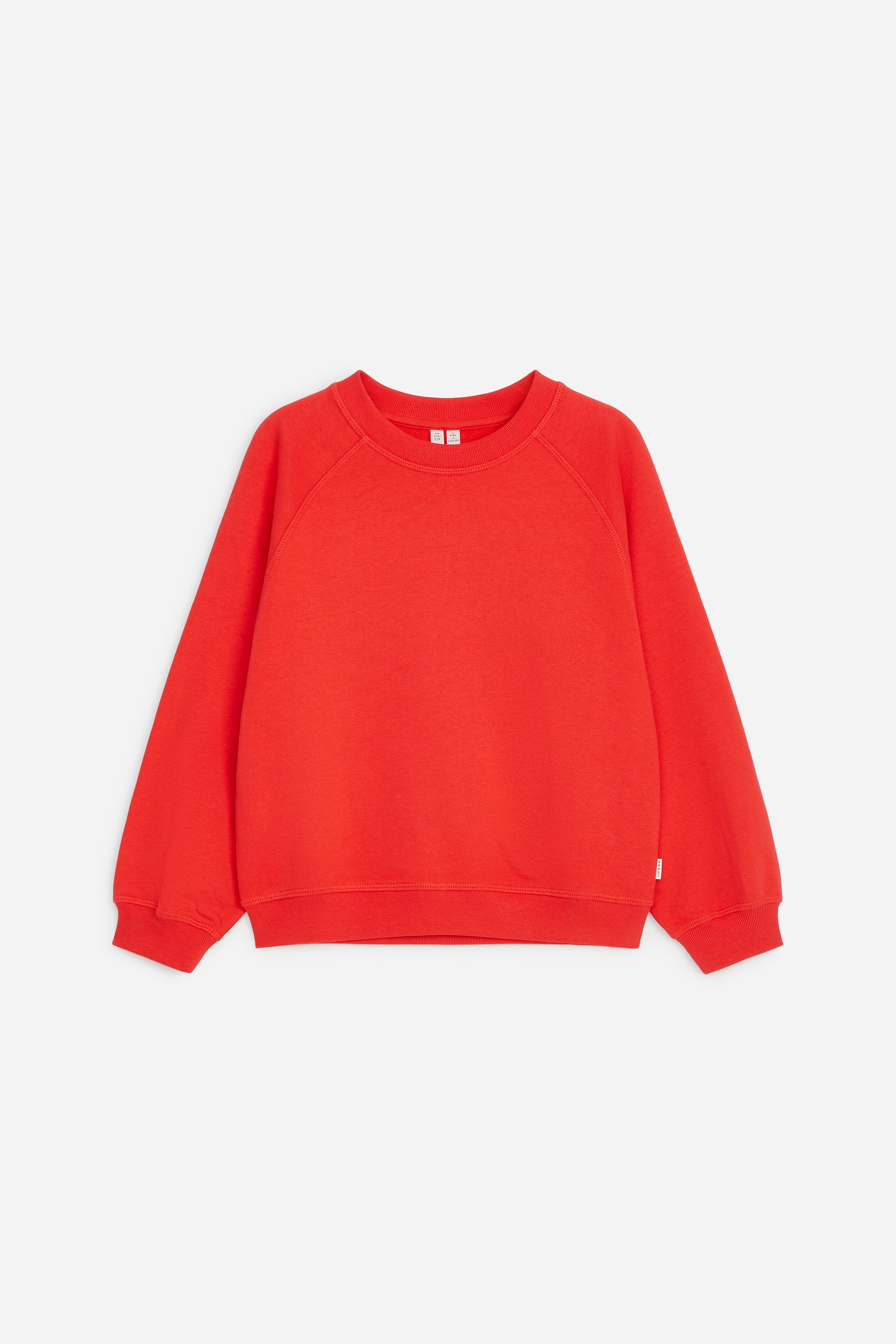 Visualizza immagine più grande: Una felpa rossa in cotone è mostrata frontalmente, con classico girocollo e maniche raglan. Presenta una vestibilità rilassata con bordi a coste su scollo, polsini e fondo.