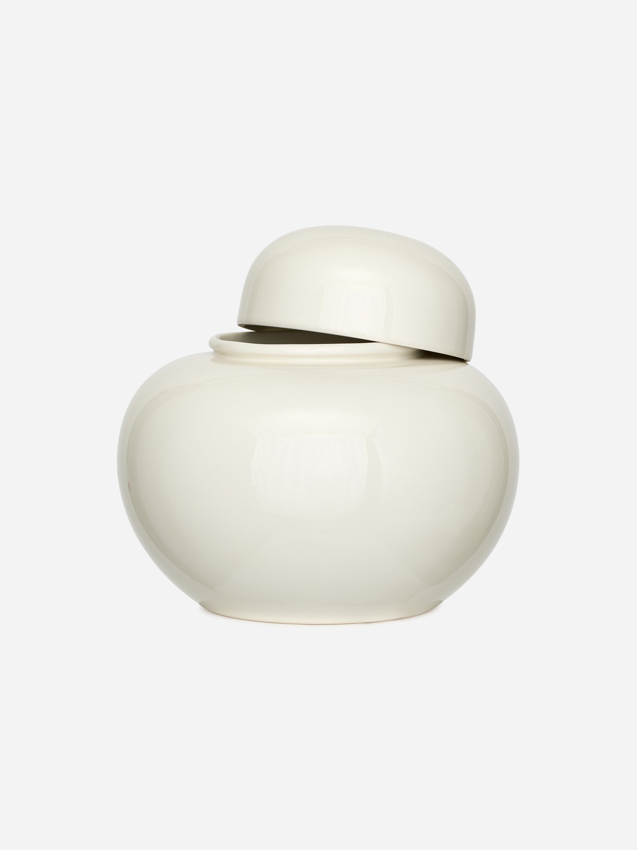 Agrandir l'image: Un pot de couleur crème présente une finition brillante et un corps arrondi et globuleux. Son couvercle en forme de dôme repose légèrement de travers sur l'ouverture du pot, créant un petit espace visible.