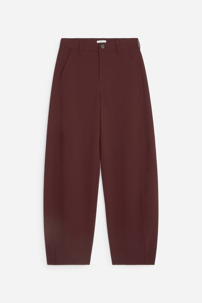 Diese dunkelburgunderfarbenen Hose aus Wollmischung, von vorne gezeigt, verfügen über eine entspannte Barrel-Leg-Silhouette mit dezent geschwungenen äußeren Nähten. Die Hose zeigt einen Bund mit Gürtelschlaufen, einen einzelnen Knopfverschluss und schräge Vordertaschen. - 1