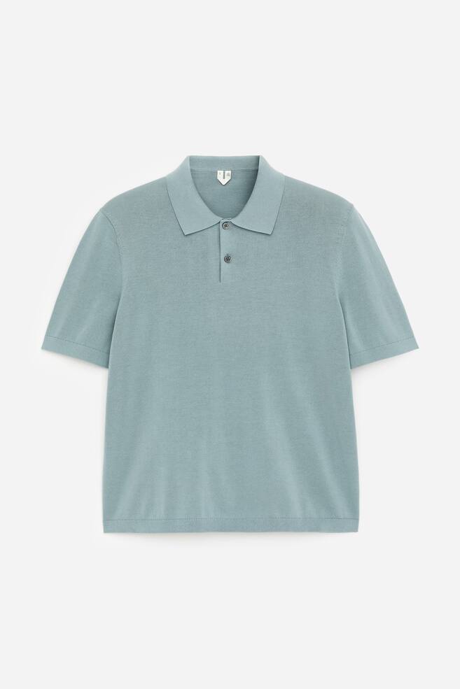 A light blue-green polo shirt crafted from fine knit fabric, featuring a classic short-sleeve design with a pointed collar and a two-button placket at the front, fastened with dark buttons. It showcases a straight hem. - 1