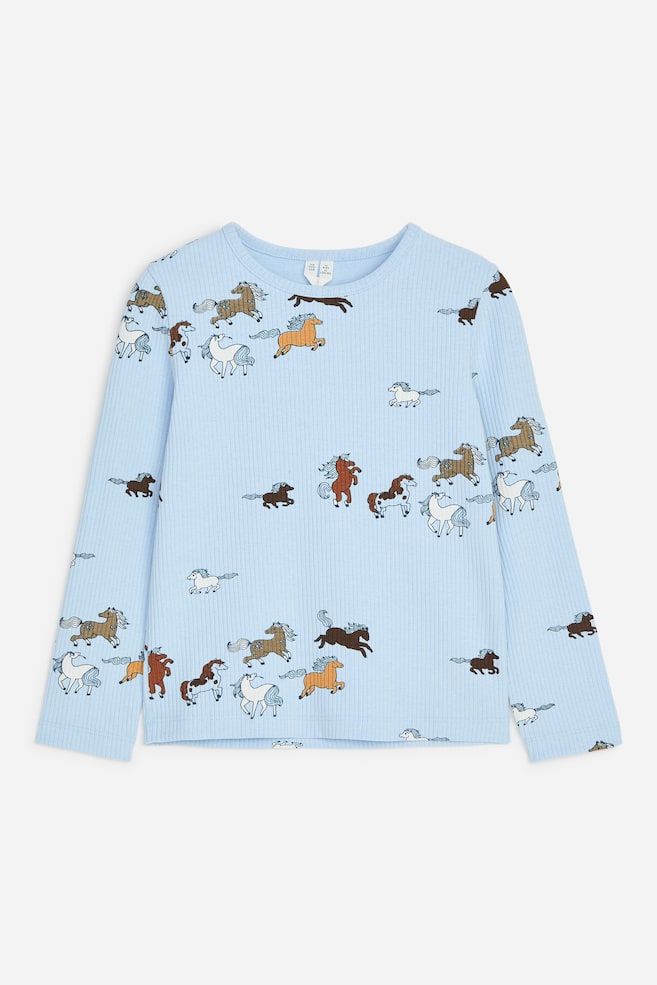 Un top a maniche lunghe a costine di colore azzurro chiaro è mostrato frontalmente, caratterizzato da una stampa all-over di cavalli al galoppo in tonalità di marrone, bianco e beige. Il top presenta uno scollo rotondo, un orlo dritto e una vestibilità regolare. - 1