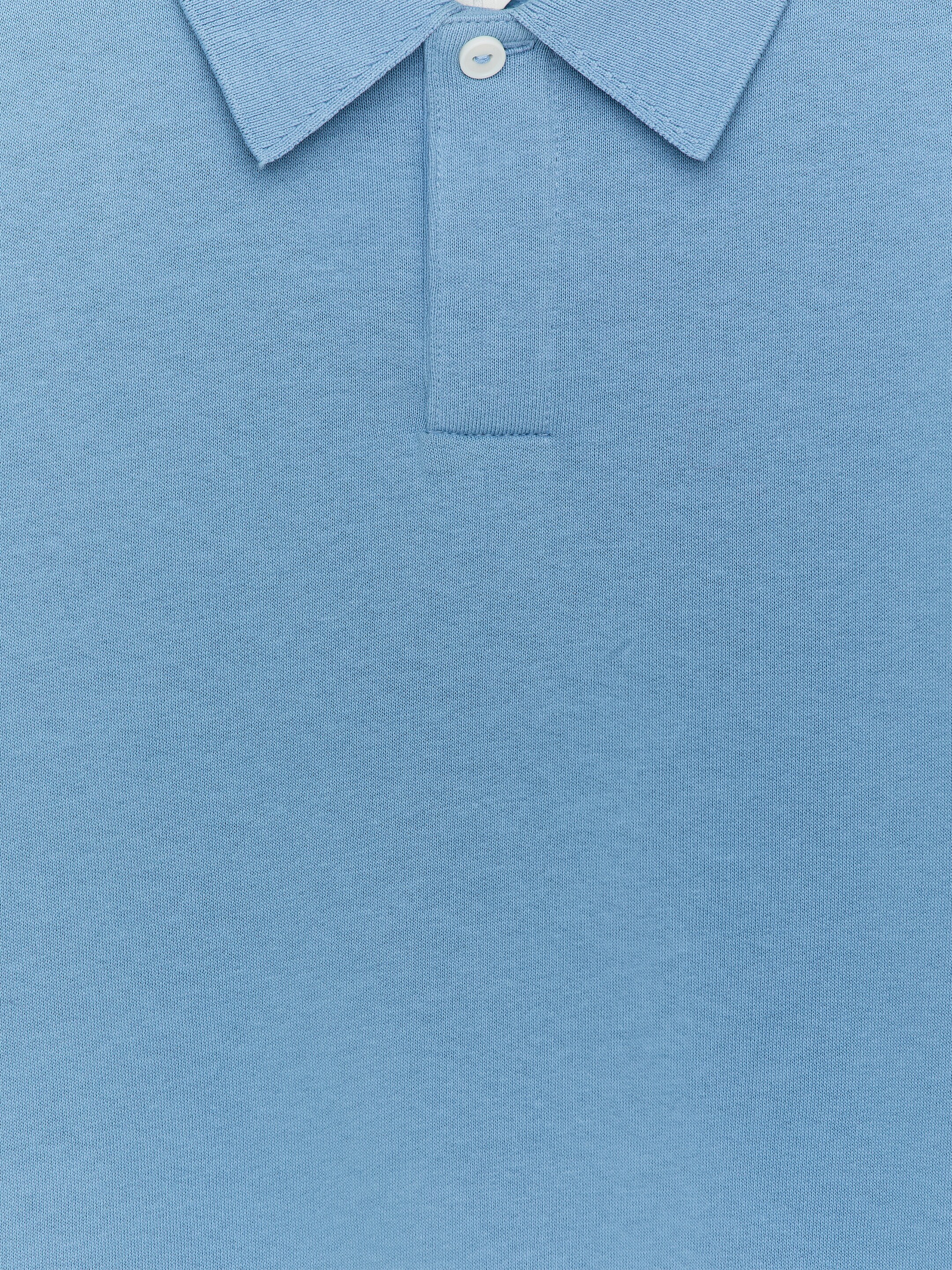 Agrandir l'image: Un polo bleu clair est présenté de face, avec un col polo classique et une patte de boutonnage avec un bouton blanc visible. La chemise est faite d'un tissu en maille piquée.