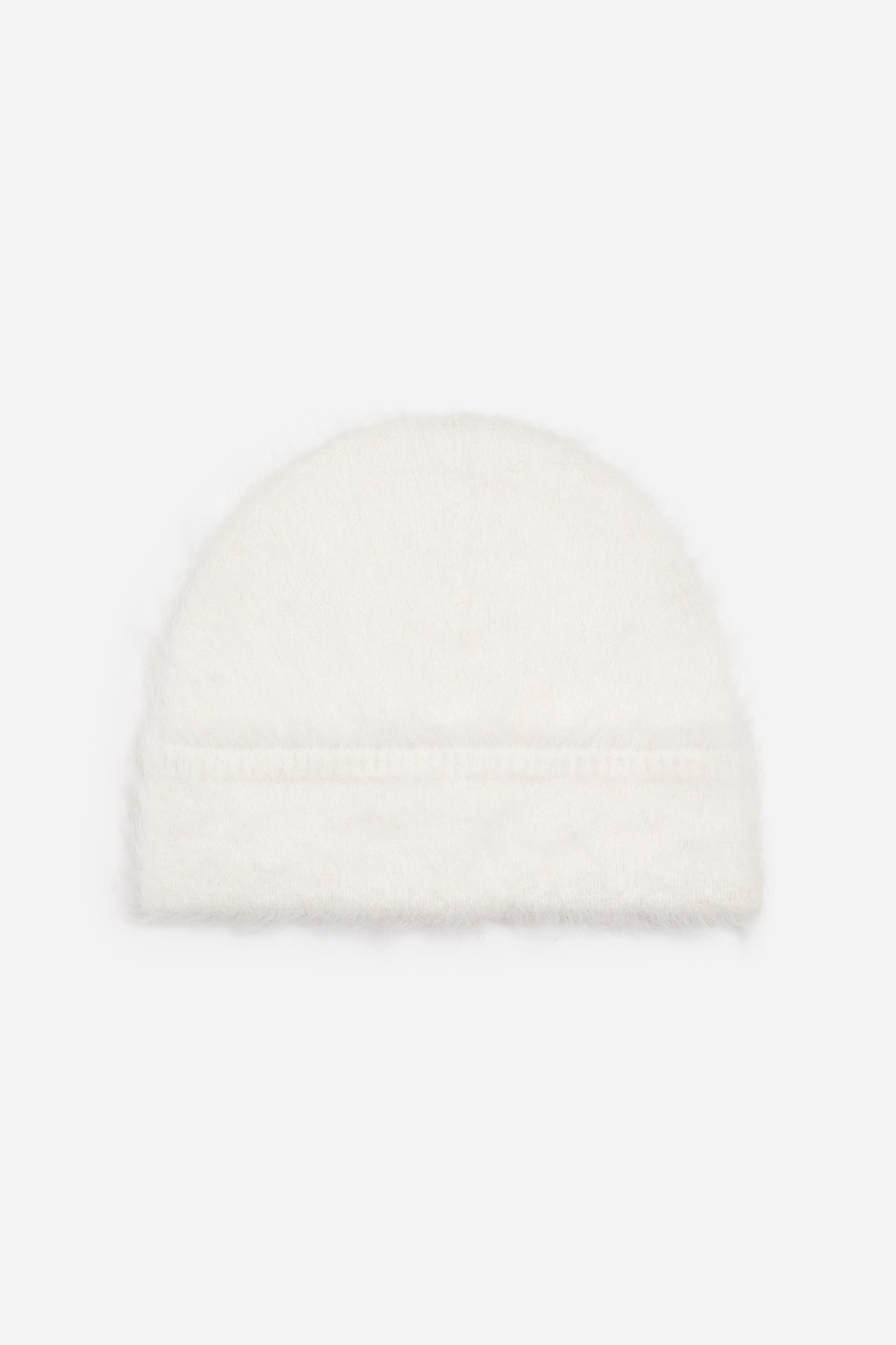 View larger image: A white fluffy beanie is shown from the front, featuring a soft, textured finish with a folded brim and a rounded crown.