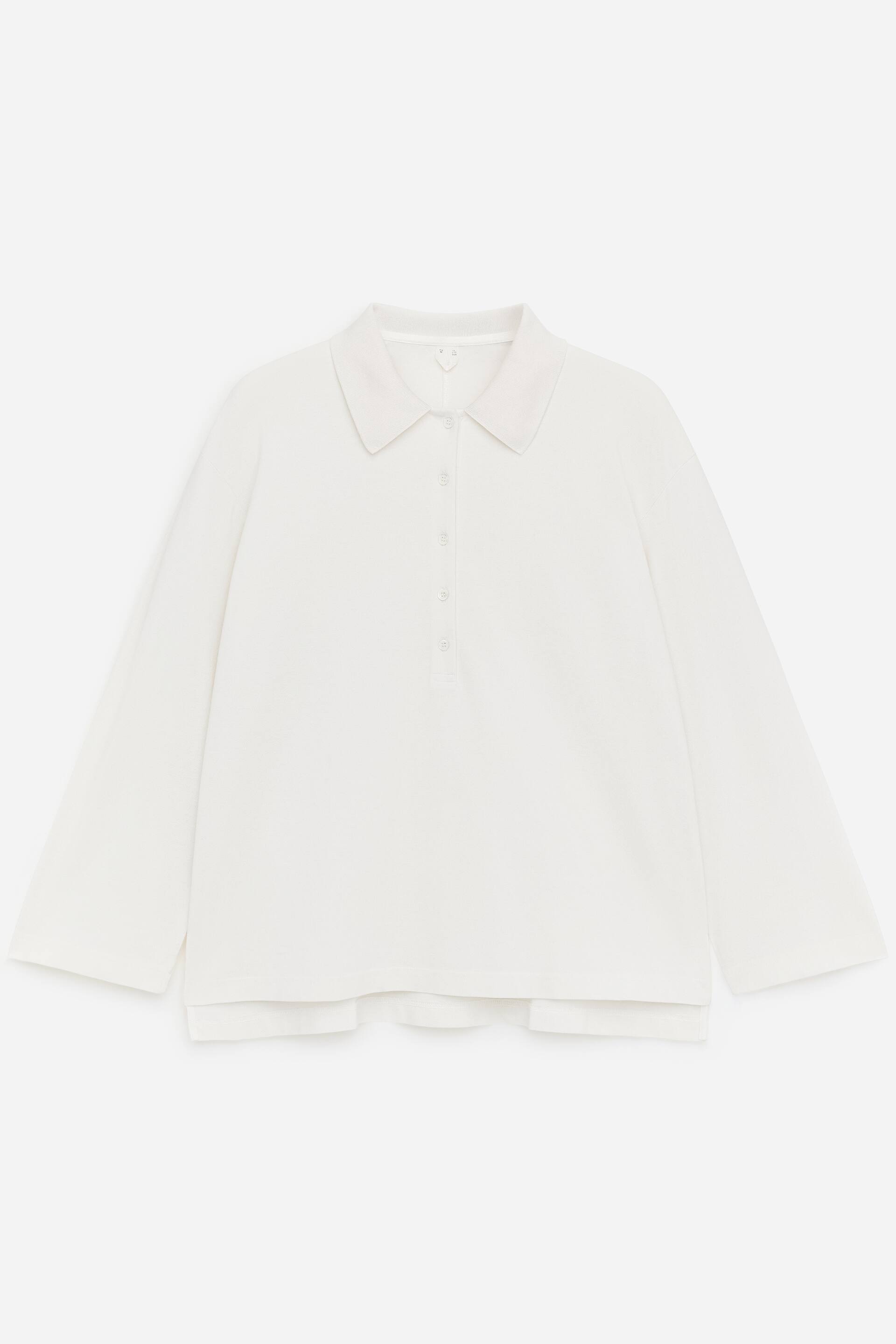 Größeres Bild anzeigen: Das Piqué-Poloshirt präsentiert sich mit einem klassischen Kragen und einer Fünf-Knopf-Leiste von vorne. Das cremefarbene Shirt zeigt lange Ärmel und ein geschichtetes Saumdetail.