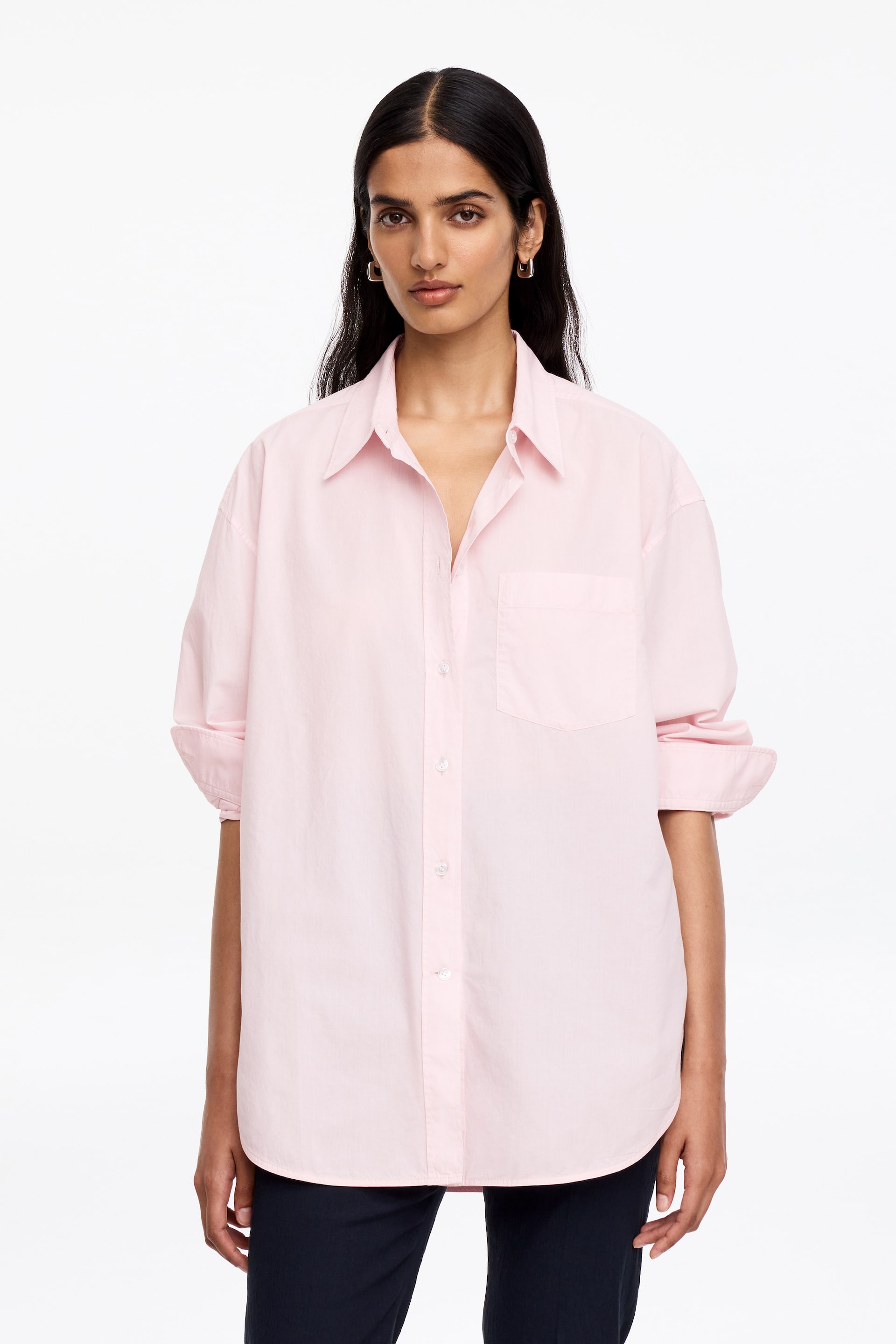 Agrandir l'image: Une chemise rose clair à boutons est dotée d'un col pointu, d'une patte de boutonnage complète avec des boutons blancs et d'une poche plaquée sur la poitrine gauche. Ses manches longues sont retroussées et son ourlet est arrondi.