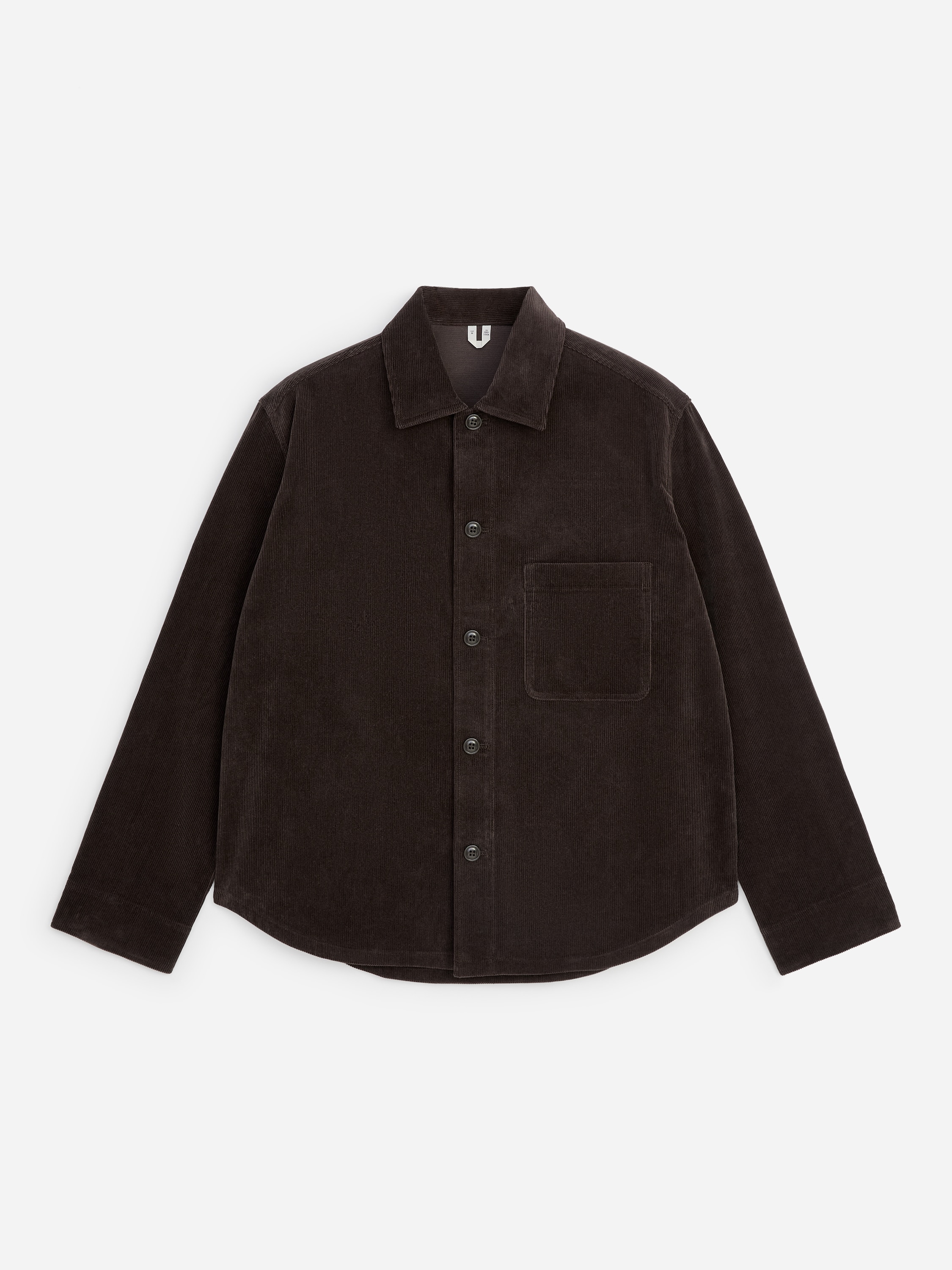 Mostrada de frente, una sobrecamisa de pana marrÃ³n oscuro con textura de canalÃ© fino y cuello clÃ¡sico se lleva abierta sobre un polo de punto fino azul marino oscuro con tapeta abotonada.