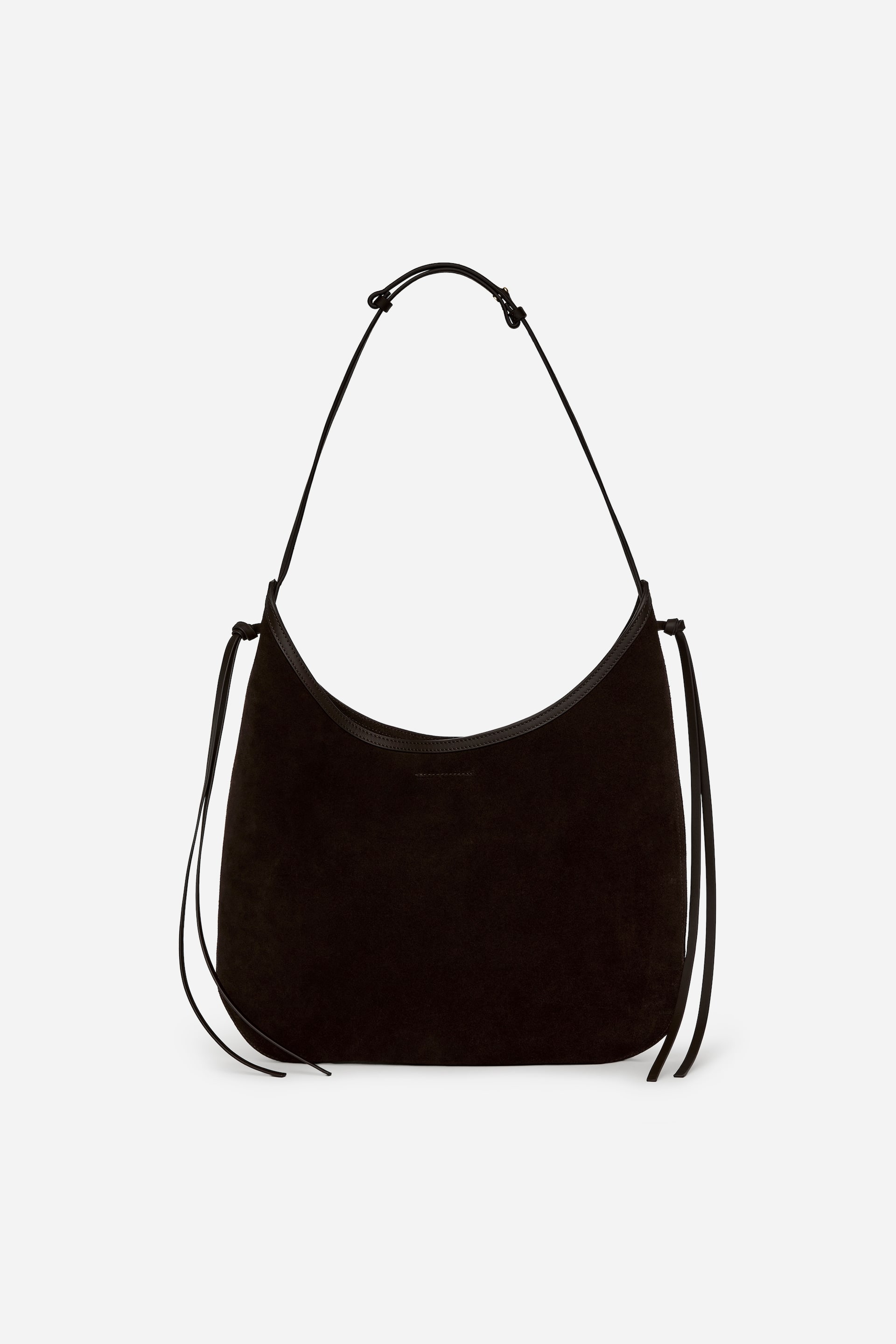 View larger image: A black suede crescent-shaped hobo bag is facing FRONT, displaying a thin black shoulder strap knotted at each side. Long, thin ties are hanging from the bag's sides, and a darker trim is bordering the top opening.