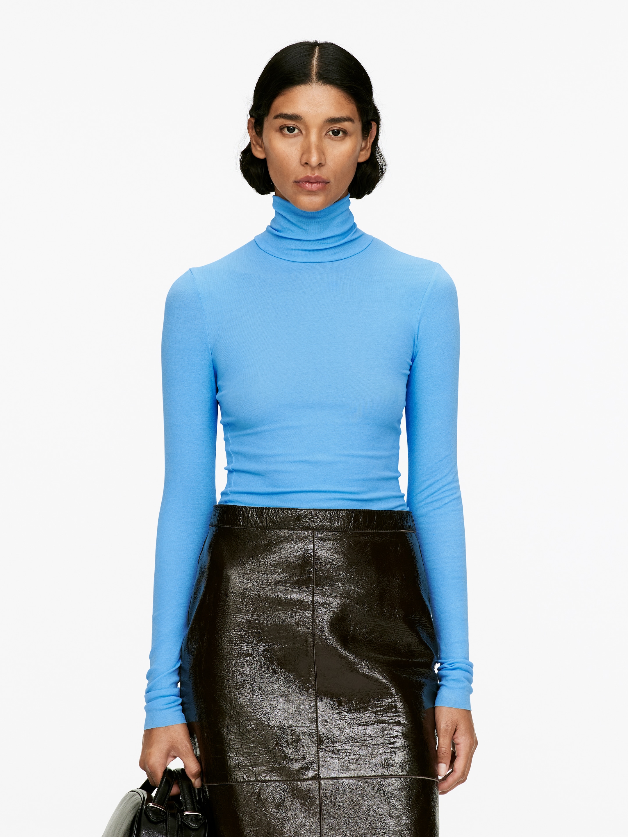 Agrandir l'image: Un haut à col roulé ajusté de couleur bleu clair est présenté, avec des manches longues et un col roulé doux. Il est assorti d'une mini-jupe marron foncé à haute brillance, conçue avec des panneaux visibles.