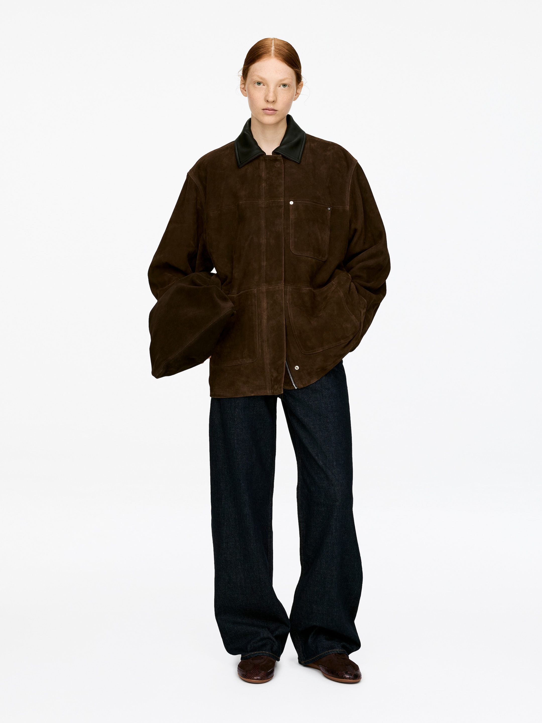 View larger image: Dark brown slip-on shoes are being worn by the model. They are featuring a textured surface and a flat sole.