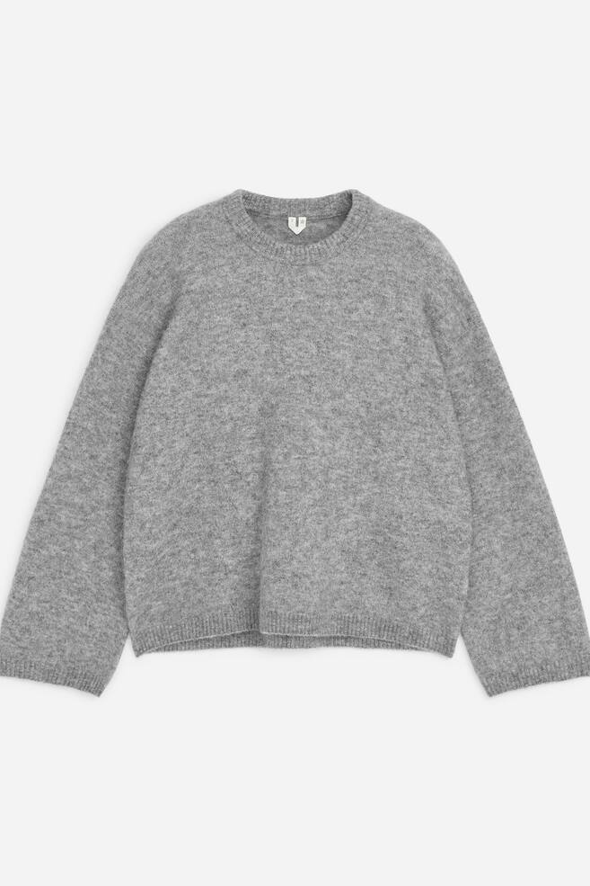 A grey crew-neck jumper is shown from the front, showcasing a fuzzy, textured knit design with a relaxed fit. The jumper features a ribbed collar, a ribbed hem, and long, slightly flared sleeves with ribbed cuffs. - 1