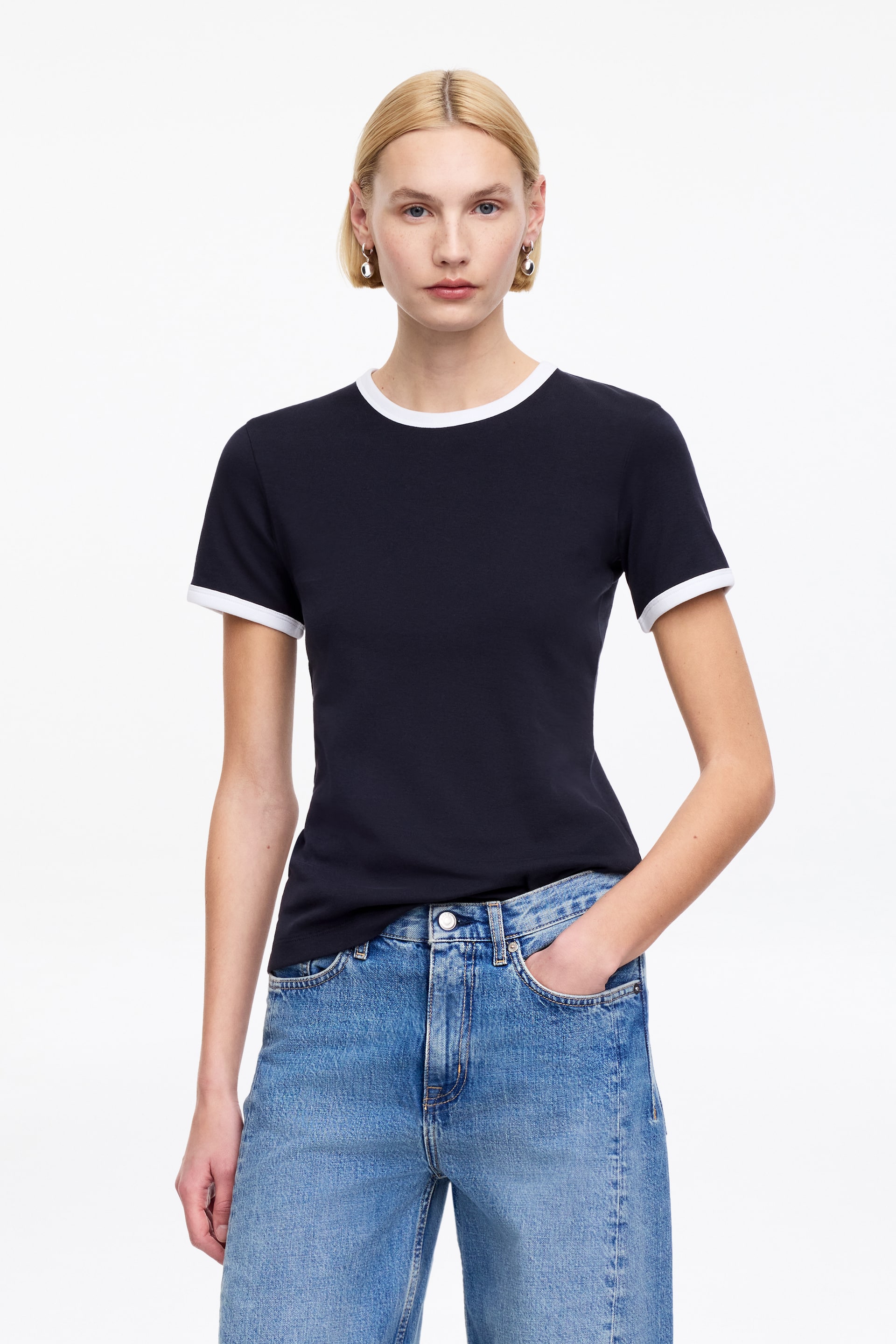 Visa större bild: En marinblå ringer t-shirt med vit kontrasterande kant på sin rundhals och kortärmade muddar. T-shirten har en smal passform, med framsidan vänd framåt.