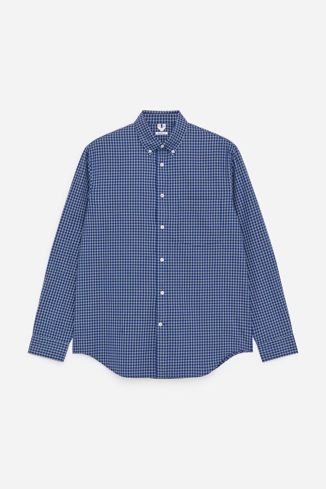 A relaxed shirt, crafted from a blue and white checkered cotton pinpoint weave, is displayed from the FRONT. It features a button-down collar, a front buttoning placket, a single chest pocket, buttoned cuffs, and mother of pearl buttons. - 1
