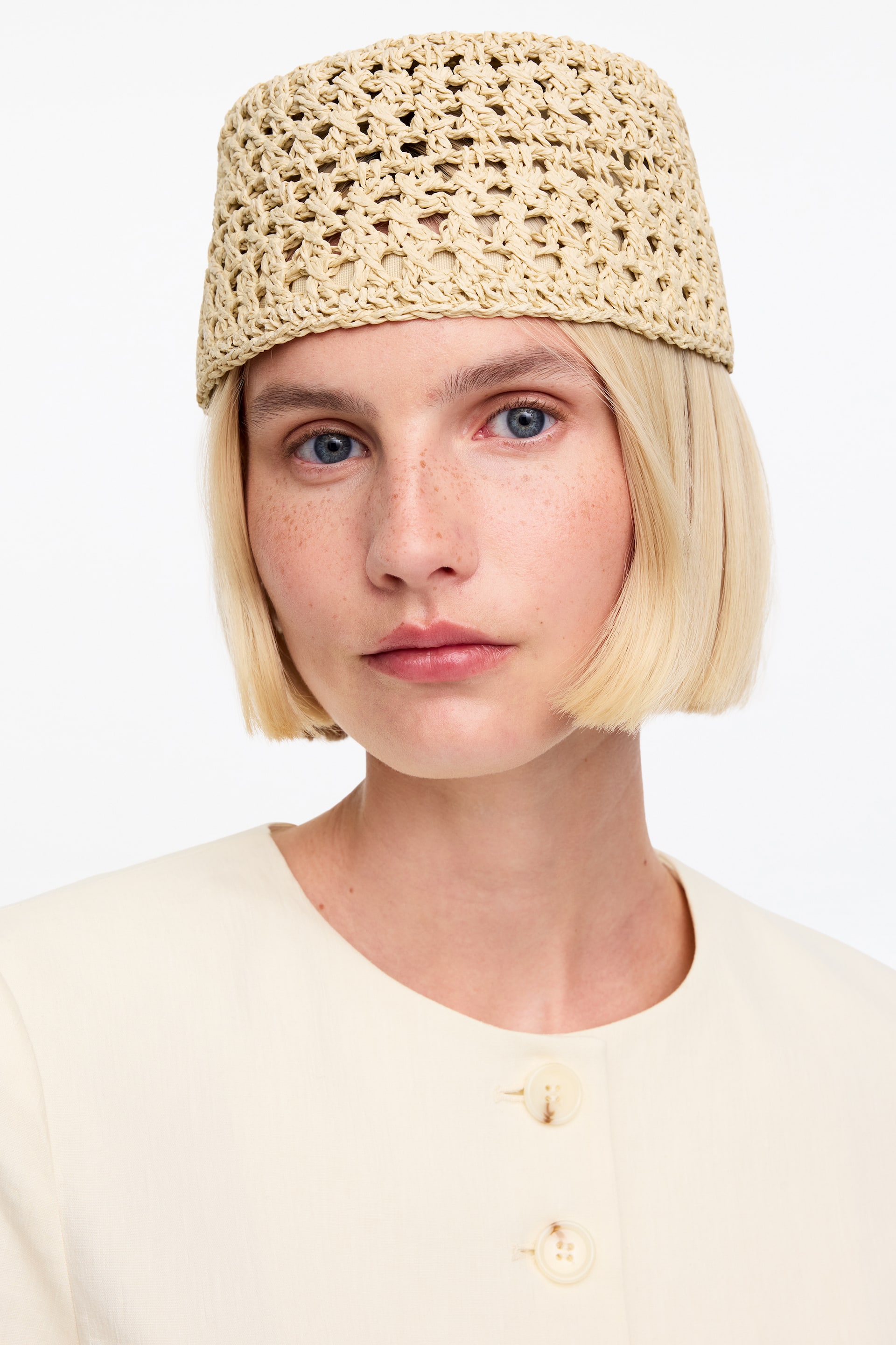 Näytä suurempi kuva: Mallilla on yllään litteälippainen, rakenteellinen paperipillistä virkattu hattu.