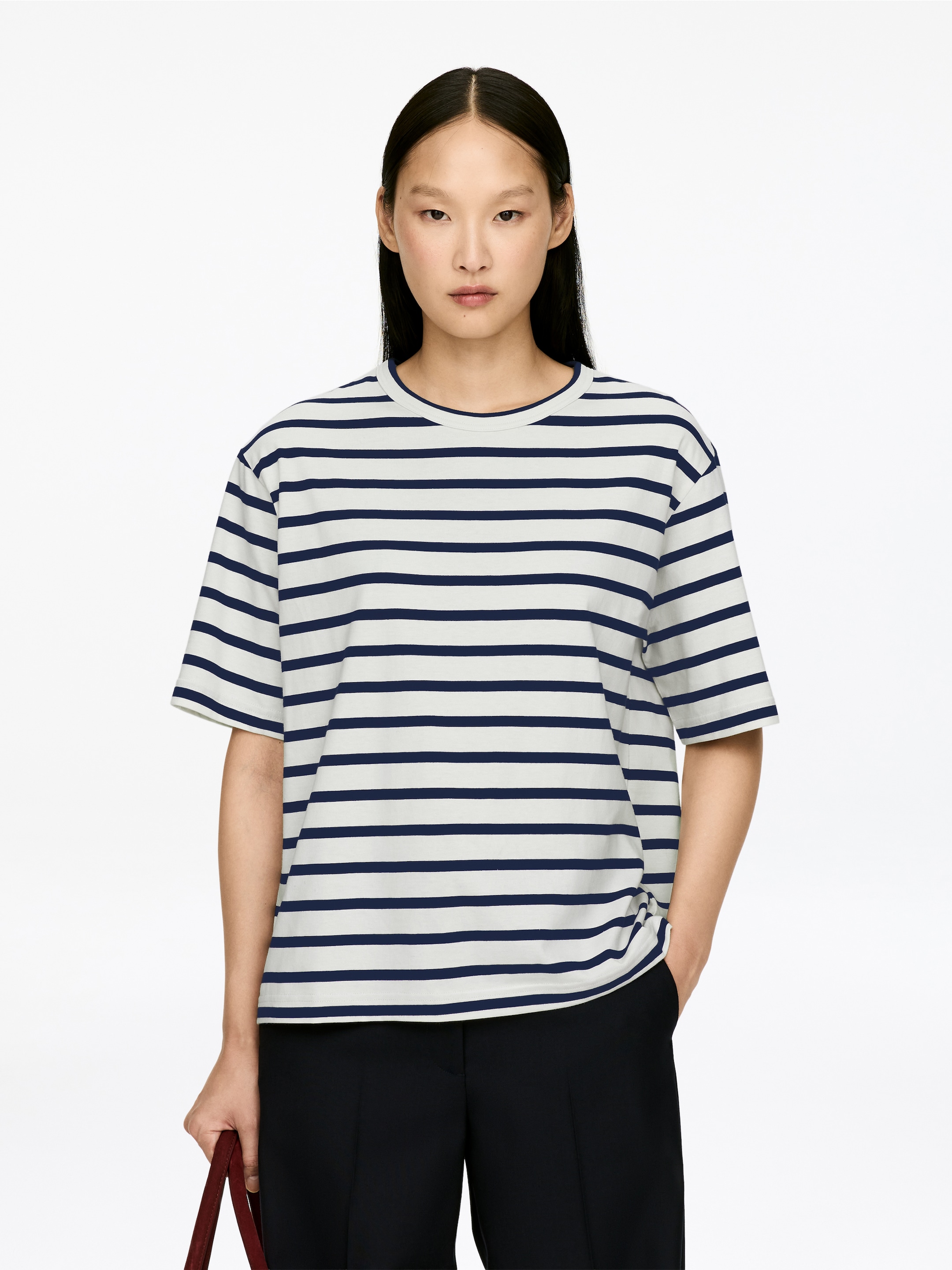 Vis større bilde: En kortermet t-skjorte viser horisontale marineblå og off-white striper, sett forfra. Den har en rund hals og en avslappet passform.