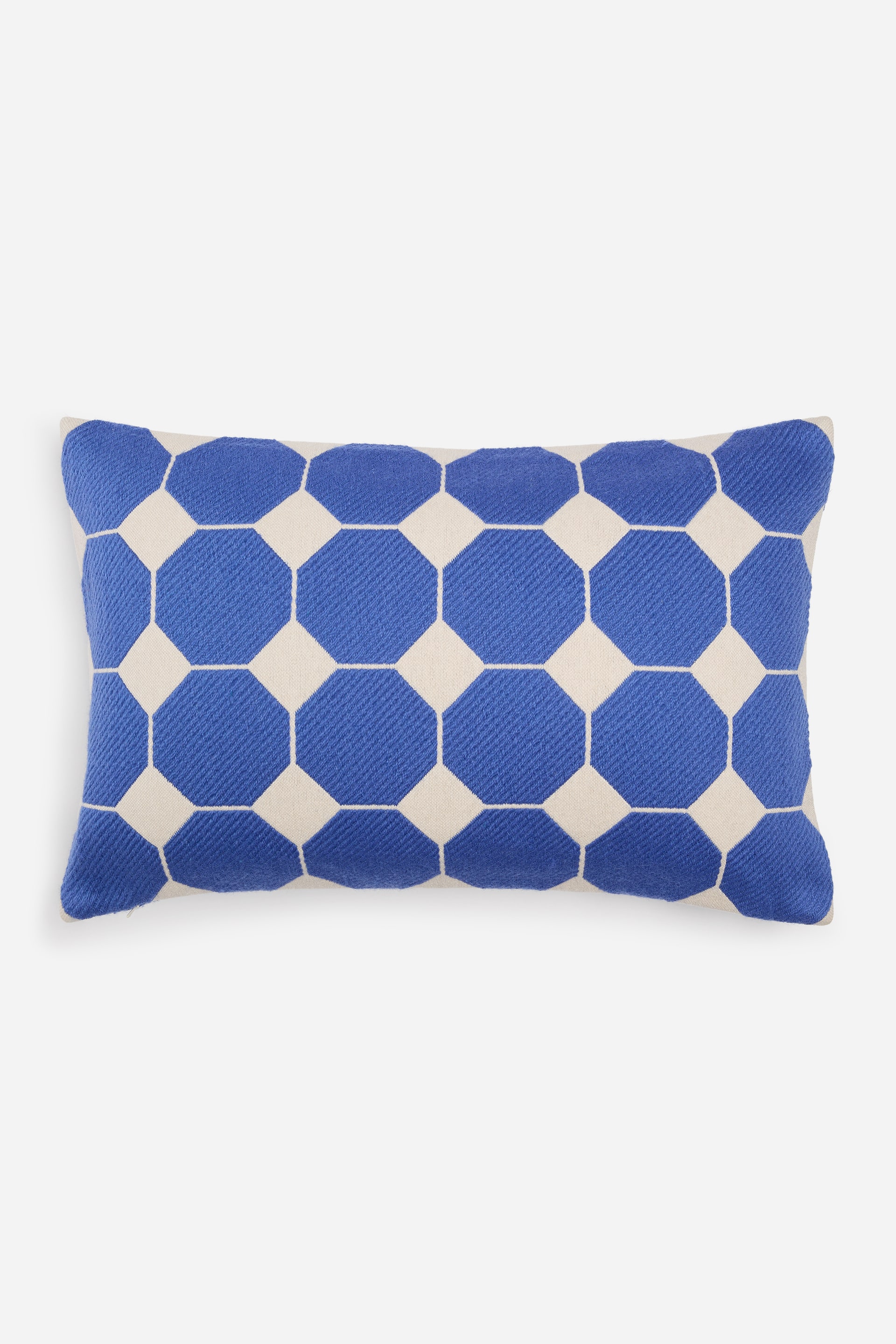 Grotere afbeelding bekijken: Een rechthoekig lendekussen is van voren te zien en toont een herhalend geometrisch patroon van blauwe achthoeken op een gebroken witte geweven stof. De blauwe vormen worden gescheiden door dunne crèmekleurige lijnen met kleine crèmekleurige ruitaccenten op de kruispunten.