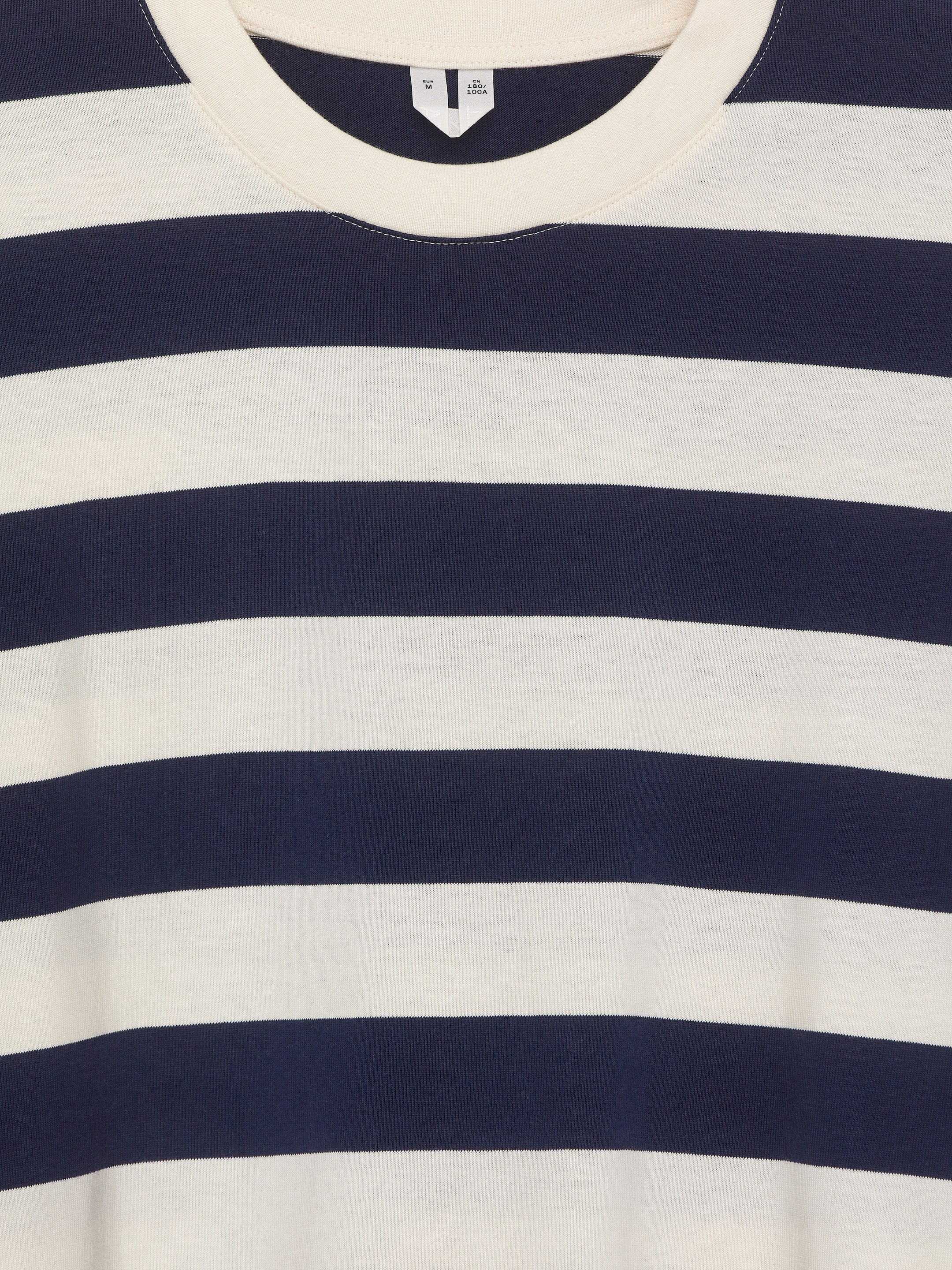 Visualizza immagine più grande: Una maglietta a maniche lunghe è mostrata dal davanti, con ampie righe orizzontali in blu navy e bianco sporco. È progettata con un collo a girocollo a coste in bianco sporco ed è realizzata in un tessuto jersey liscio.