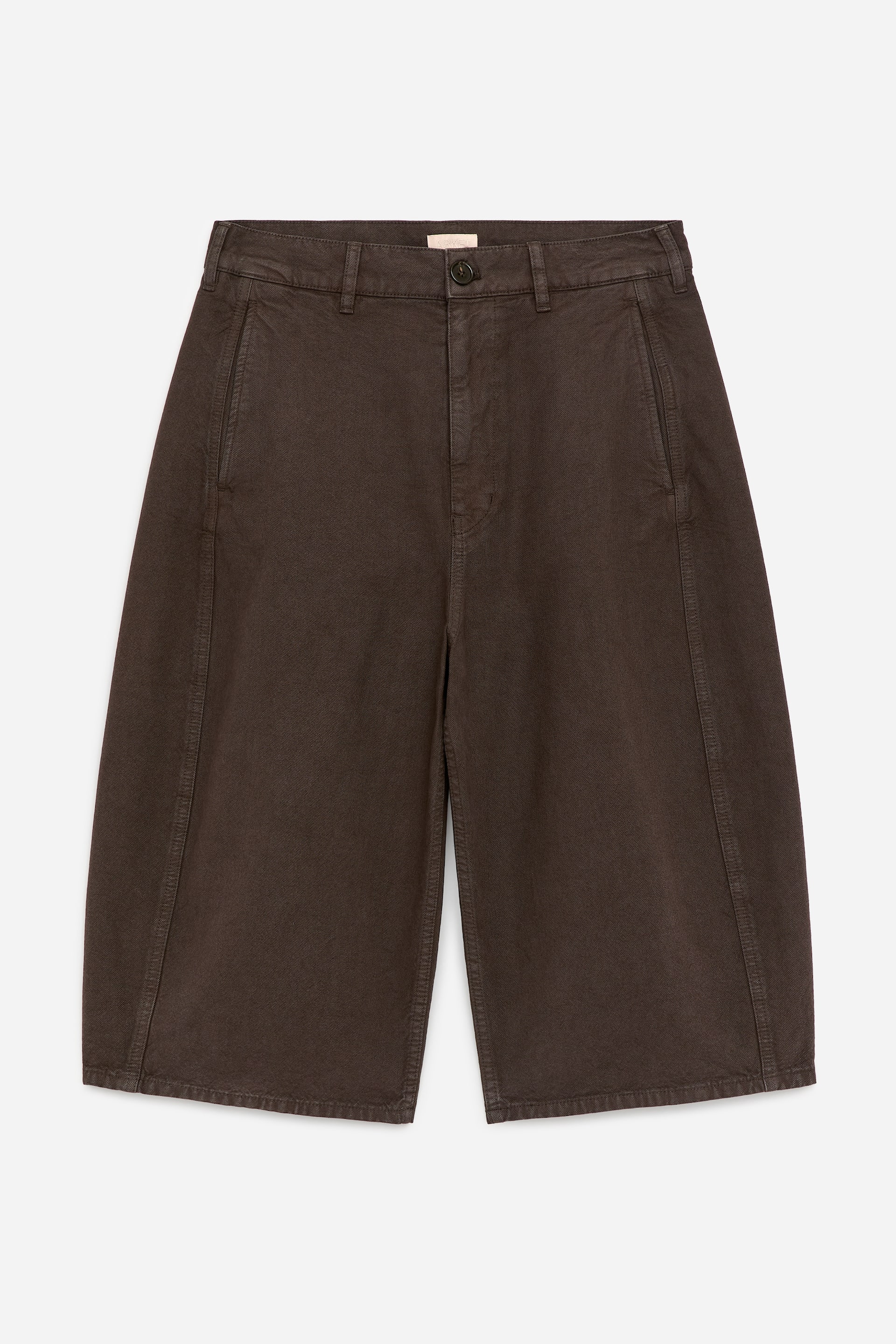 Προβολή μεγαλύτερης εικόνας: Σκούρες καφέ κουλόττες παρουσιάζουν μια εμπρόσθια όψη, αναδεικνύοντας μια ίσια ζώνη με θηλιές για ζώνη, ένα κλείσιμο με κουμπί και φερμουάρ. Διακρίνονται λοξές πλαϊνές τσέπες, μαζί με φαρδιά, κοντά μπατζάκια που διαθέτουν εμφανείς κάθετες ραφές.