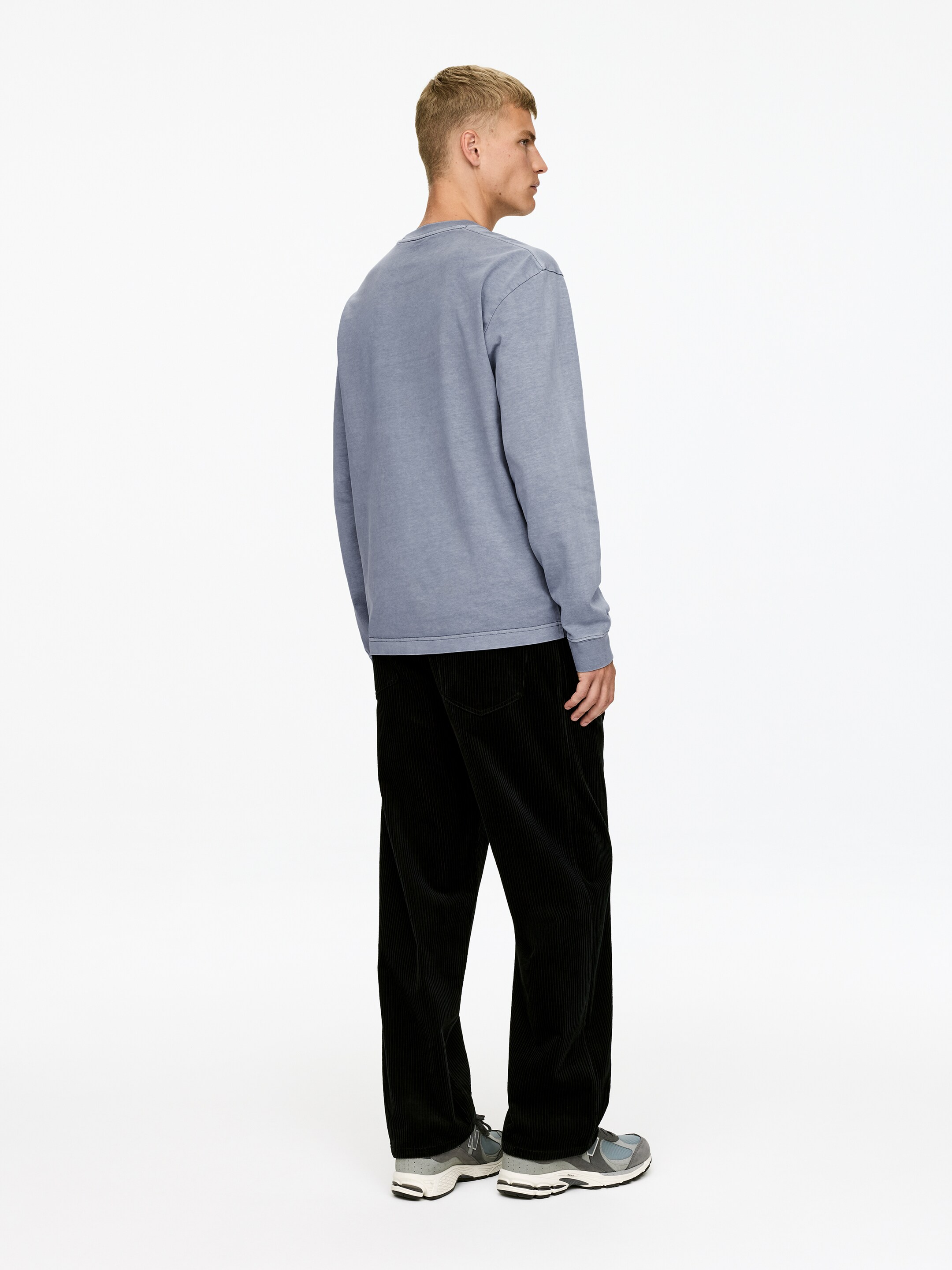 View larger image: A faded blue-grey long-sleeved sweatshirt is being presented from the back and side. It is featuring a crew neck, with ribbed cuffs and a ribbed hem.