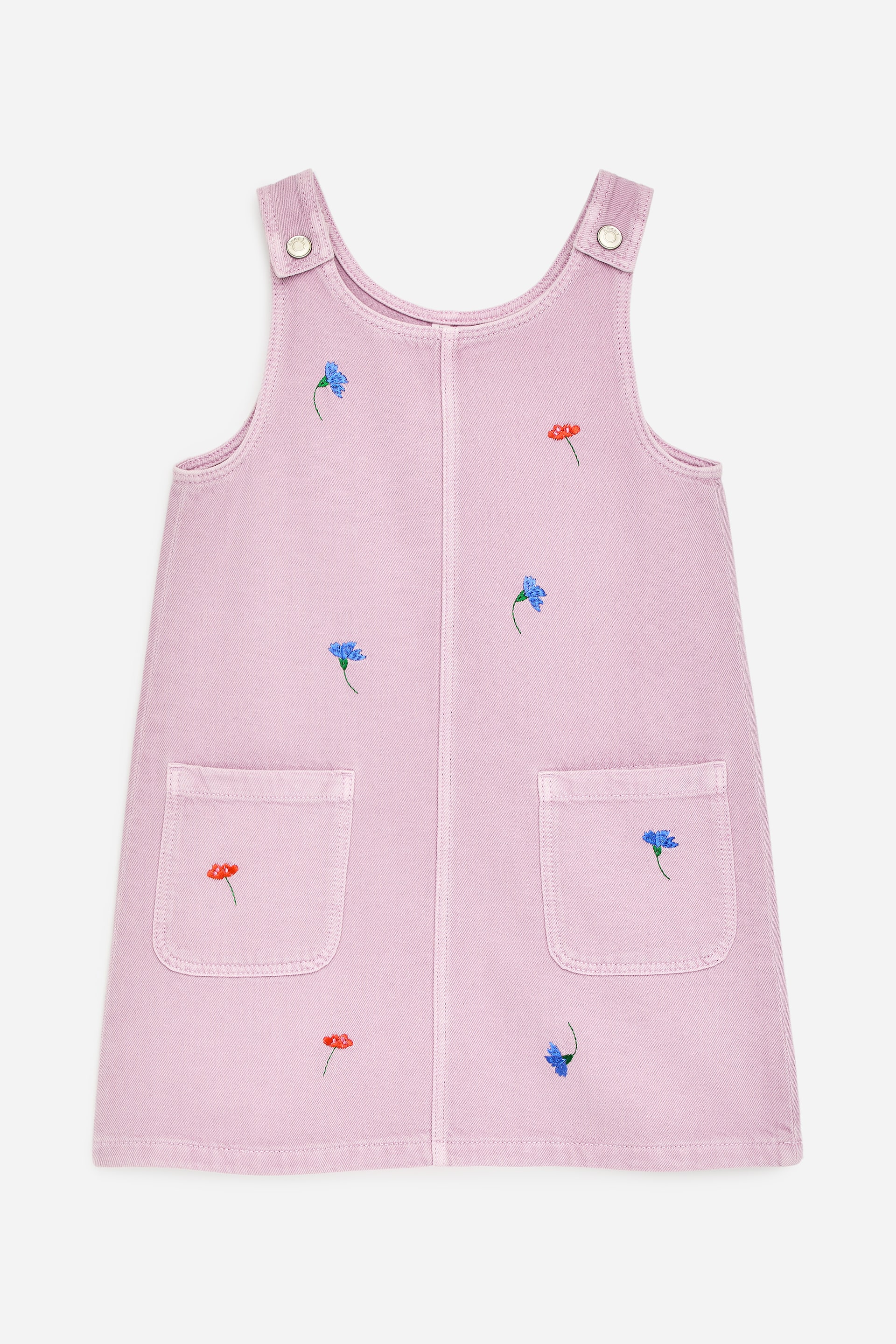 Visualizza immagine più grande: Un abito grembiule lilla chiaro mostra il suo DAVANTI, caratterizzato da due spalline con bottoni a pressione argentati, due tasche applicate e ricami floreali rossi e blu sparsi ovunque.