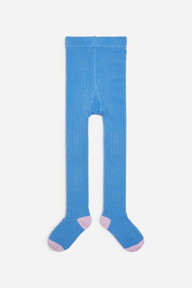 Diese blauen Strickstrumpfhosen mit Rippenstruktur sind von vorne zu sehen und verfÃ¼gen Ã¼ber ein vertikales Rippenmuster sowie einen elastischen Bund. Die FÃ¼Ãe zeigen kontrastierende hellrosa Fersen und Zehen. - 1