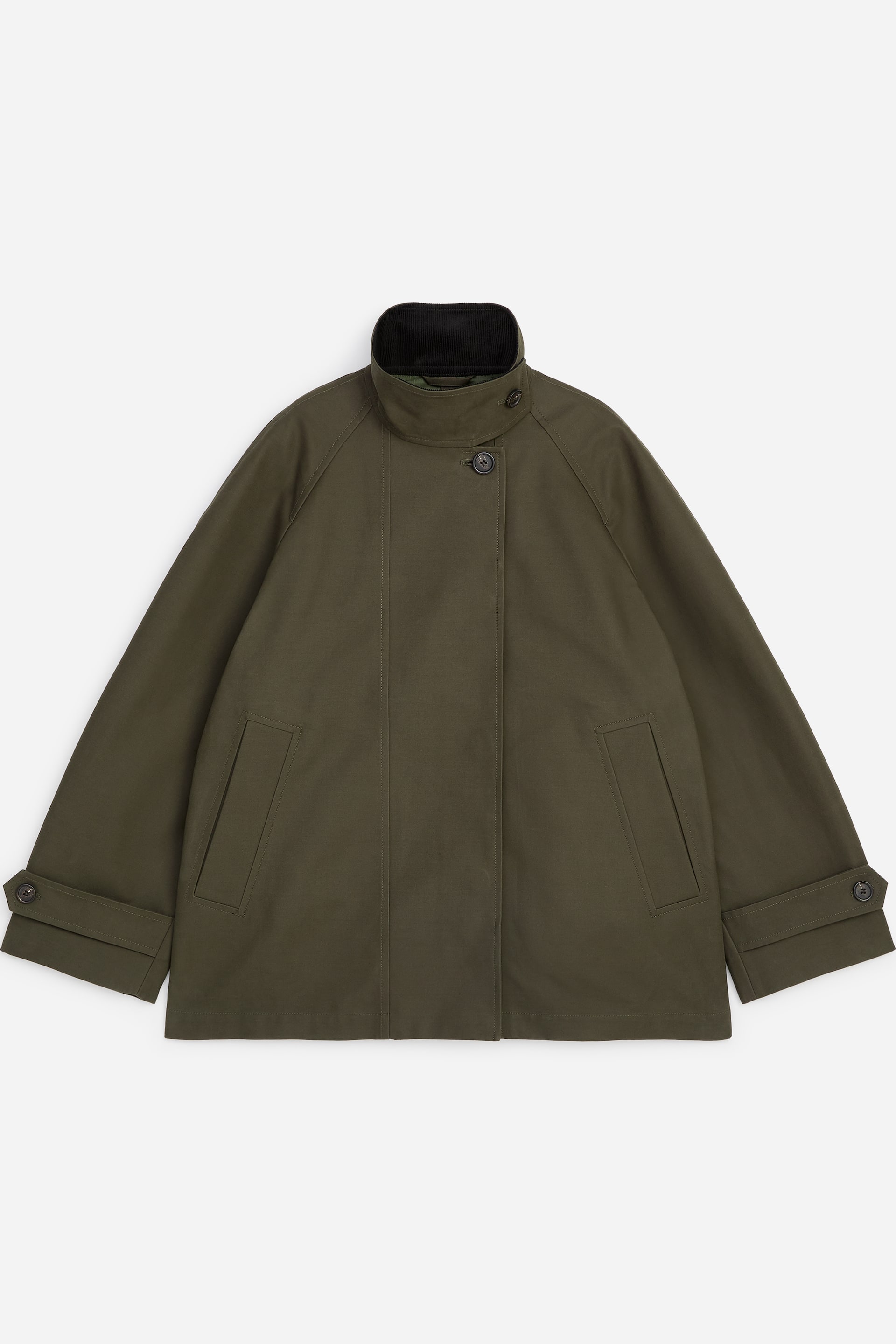 Größeres Bild ansehen: Die olivgrüne Jacke ist von vorne zu sehen und verfügt über einen stehenden schwarzen Cordkragen mit Knopfverschluss. Sie ist mit einer verdeckten Knopfleiste gestaltet, wobei ein sichtbarer oberer Knopf zu sehen ist, und zwei schräge Leistentaschen. Die weiten Ärmel enden mit verstellbaren Knopfmanschetten.
