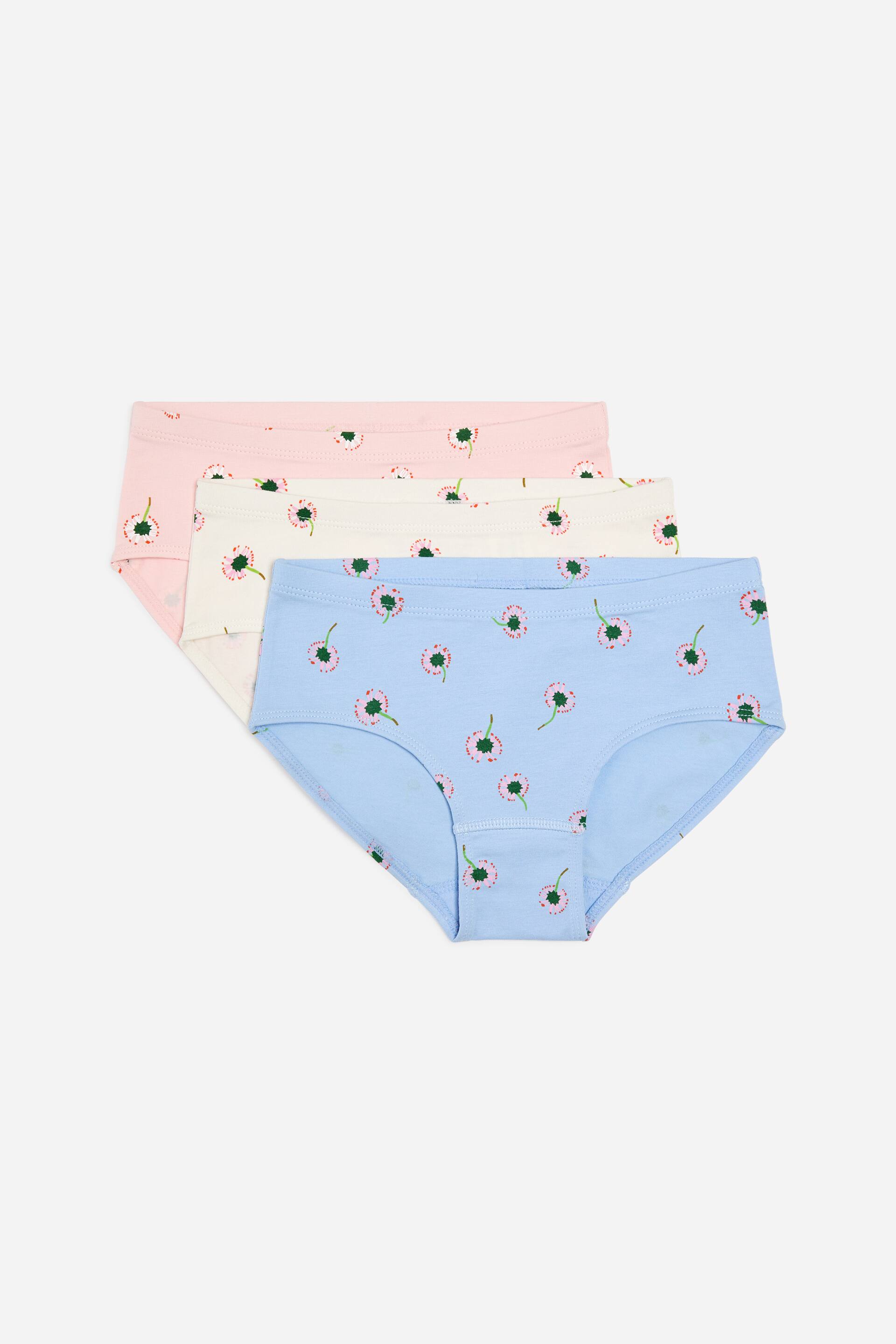 Größeres Bild ansehen: Drei weiche Baumwollslips sind gestapelt und leicht versetzt, mit der Vorderseite nach vorne. Die Slips sind hellblau, cremefarben und hellrosa, jeweils mit einem sich wiederholenden Muster aus kleinen rosa Blumen mit grünen Stielen.