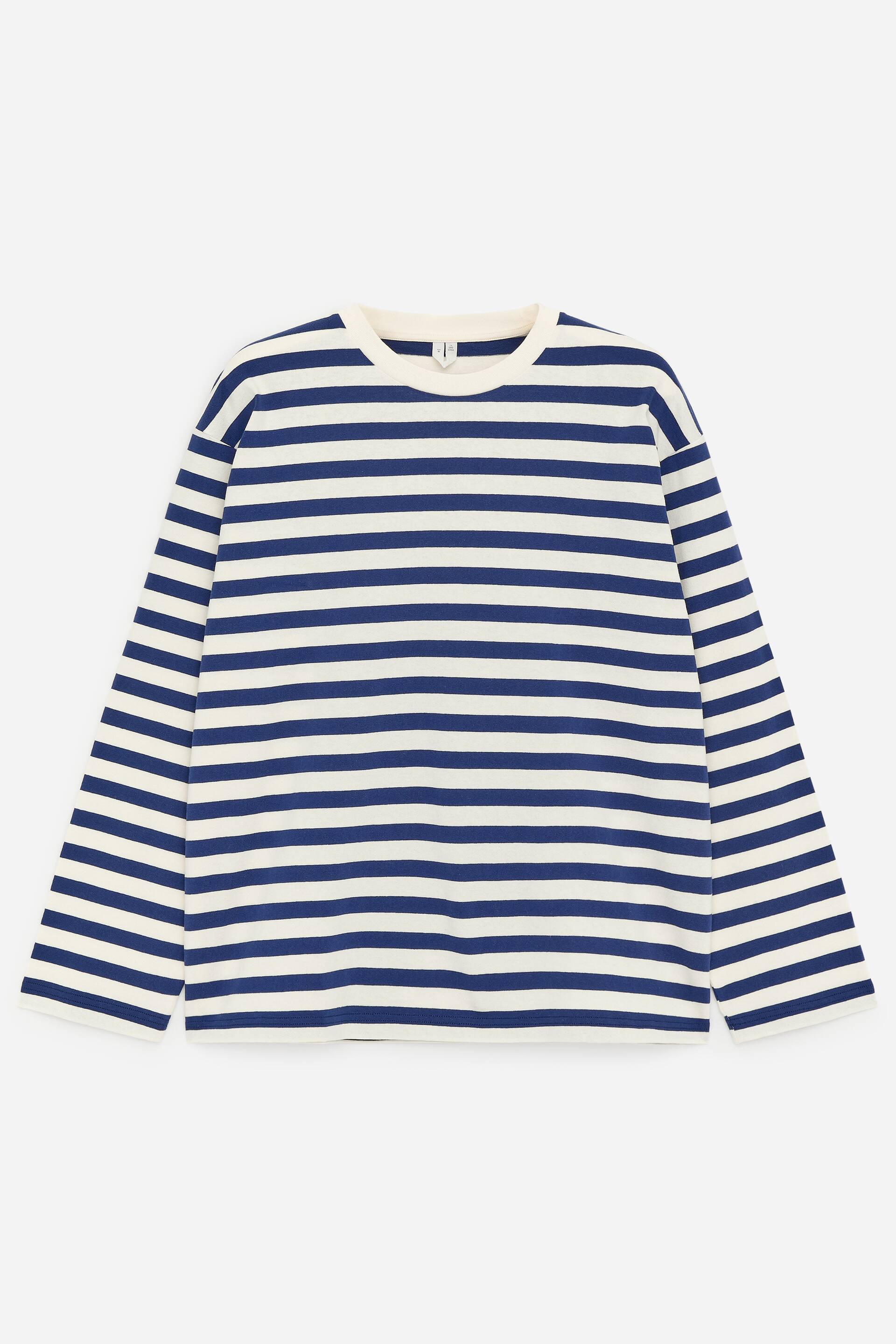 Zobrazit větší obrázek: PŘEDNÍ STRANA: Tričko s dlouhým rukávem má vodorovné pruhy v námořnické modré a krémové barvě na žerzejové pletenině. Je navrženo s kulatým výstřihem, žebrovaným lemem u krku a volným střihem, zatímco na bočních švech jsou viditelné krátké rozparky.