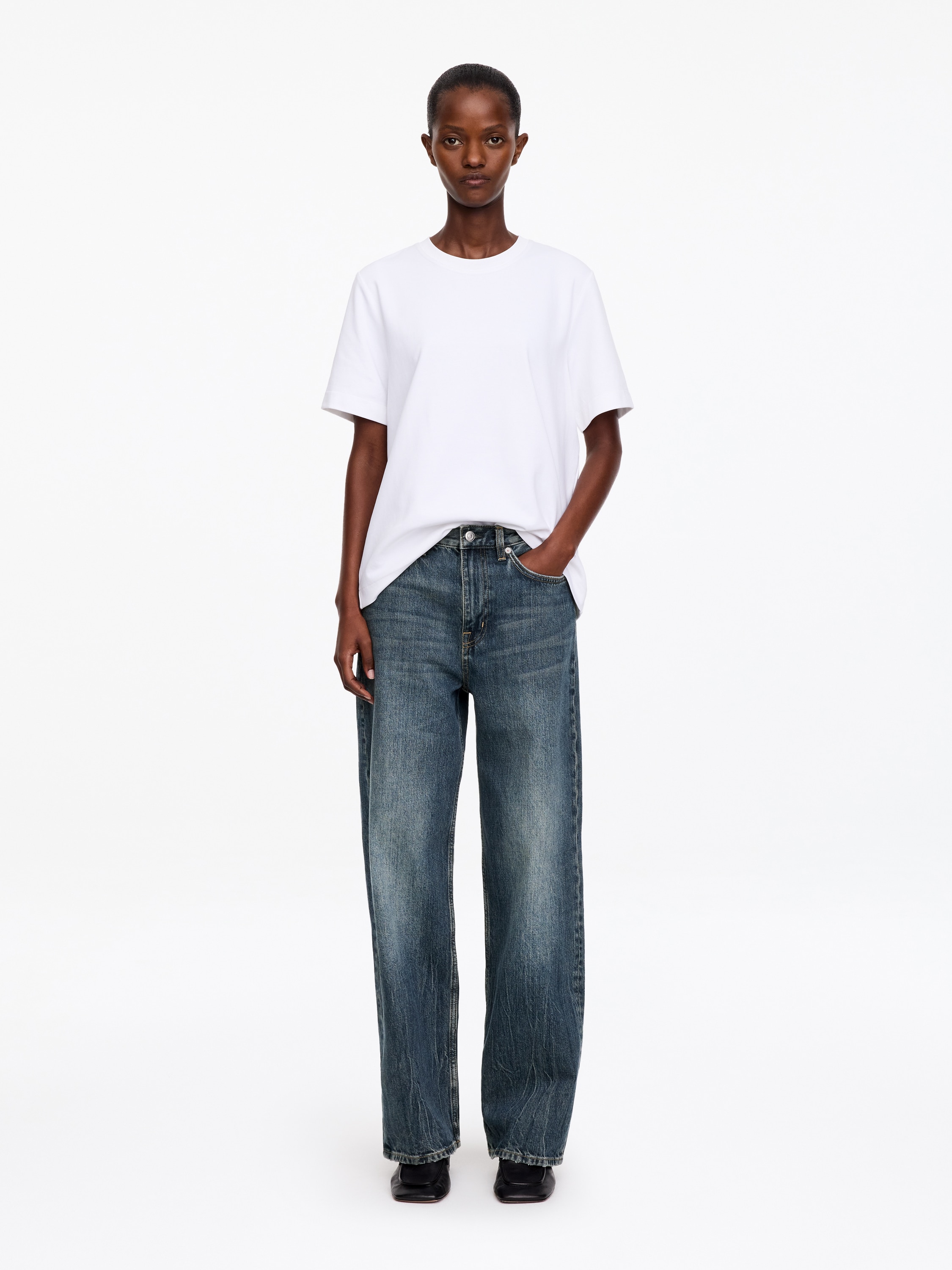 Blugii din denim cu talie înaltÄ Èi croialÄ wide-leg sunt prezentaÈi din faÈÄ, evidenÈiind o nuanÈÄ albastru mediu, cu decolorÄri subtile pe coapse Èi genunchi. AceÈtia au o construcÈie clasicÄ cu cinci buzunare, betelie cu nasture Èi închidere cu fermoar, precum Èi o siluetÄ relaxatÄ, dreaptÄ.