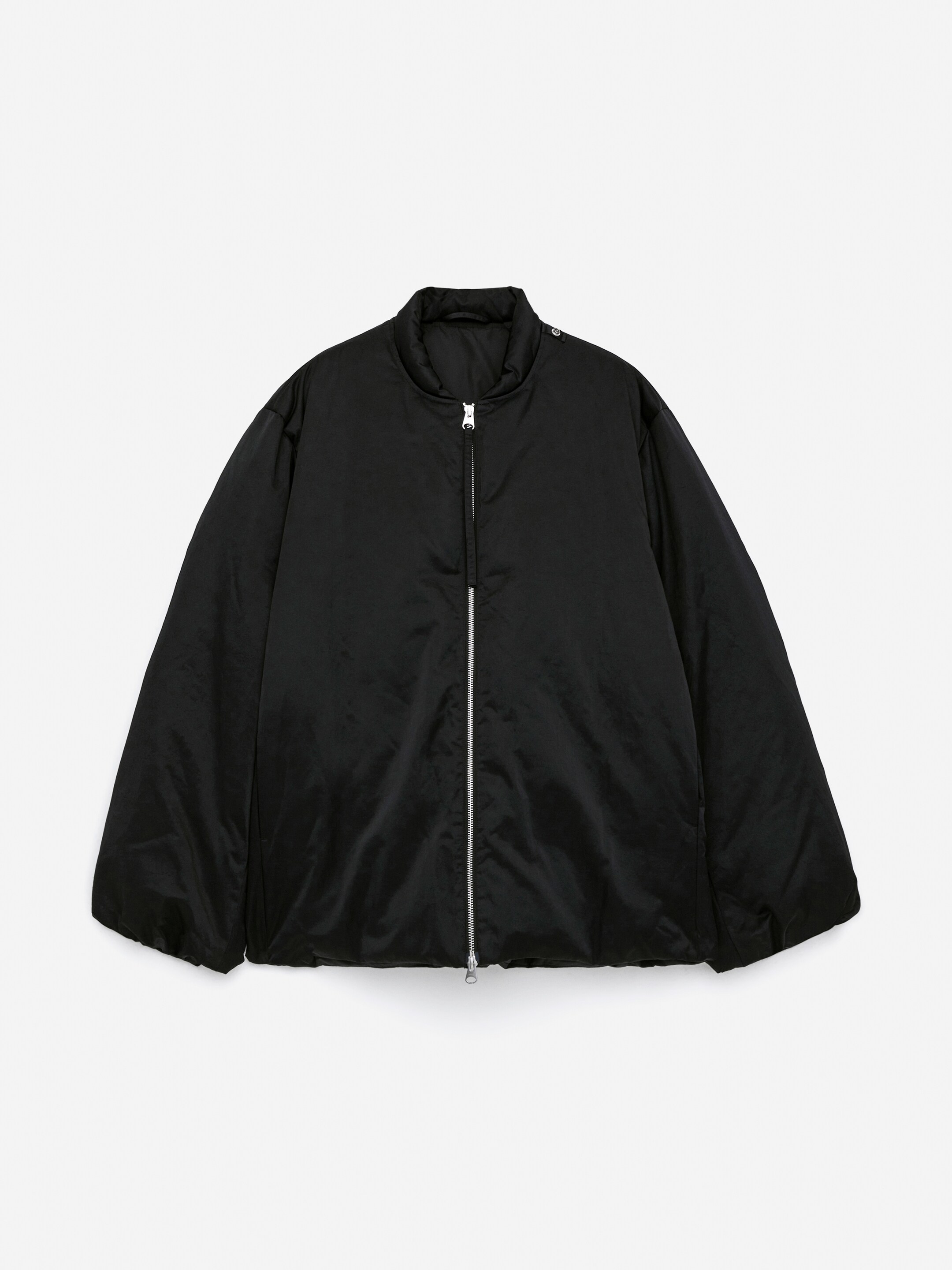 Vis større bilde: Den Upcycled Down Scarf Jacket viser sin frontvisning, med et svart, litt puffy design. En full-lengde sølvglidelås strekker seg nedover midten foran, og den har en høy ståkrage med to sølvknapper på høyre side.