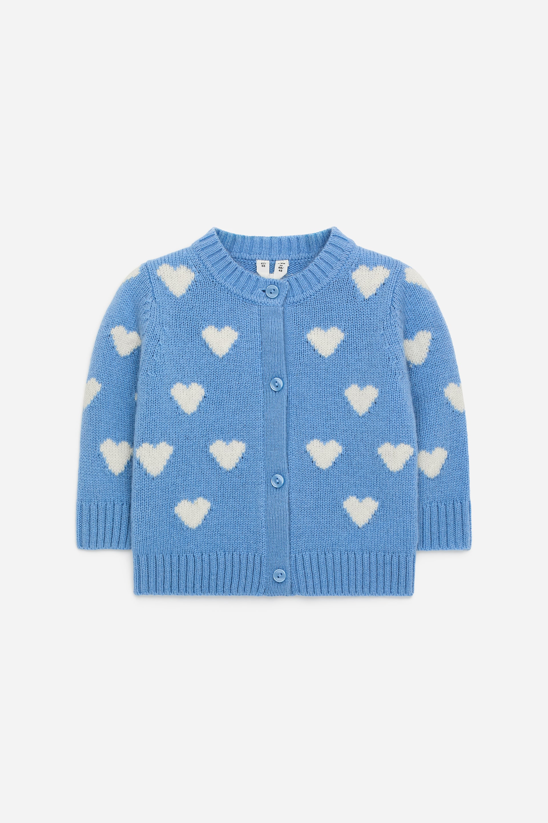 Agrandir l'image: Un cardigan en coton présente son DEVANT. Il affiche un motif en intarsia de cœurs blancs sur un fond bleu, et comprend une fermeture à boutons avec des finitions côtelées au niveau du col, des poignets et de l'ourlet.