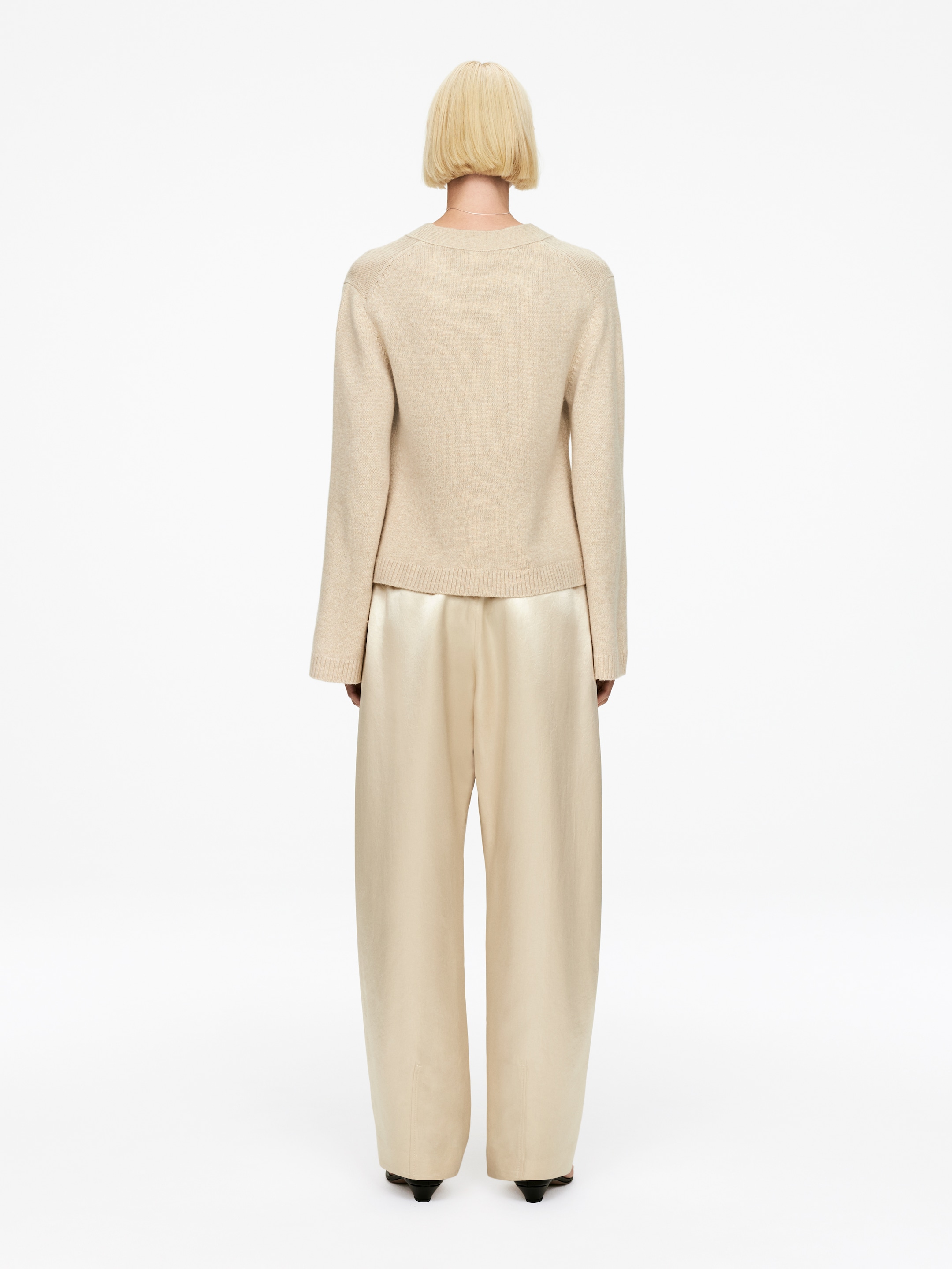 Agrandir l'image: Un pull à col rond beige clair avec des manches raglan et un ourlet côtelé est présenté de dos, superposé à un pantalon large de couleur crème clair.