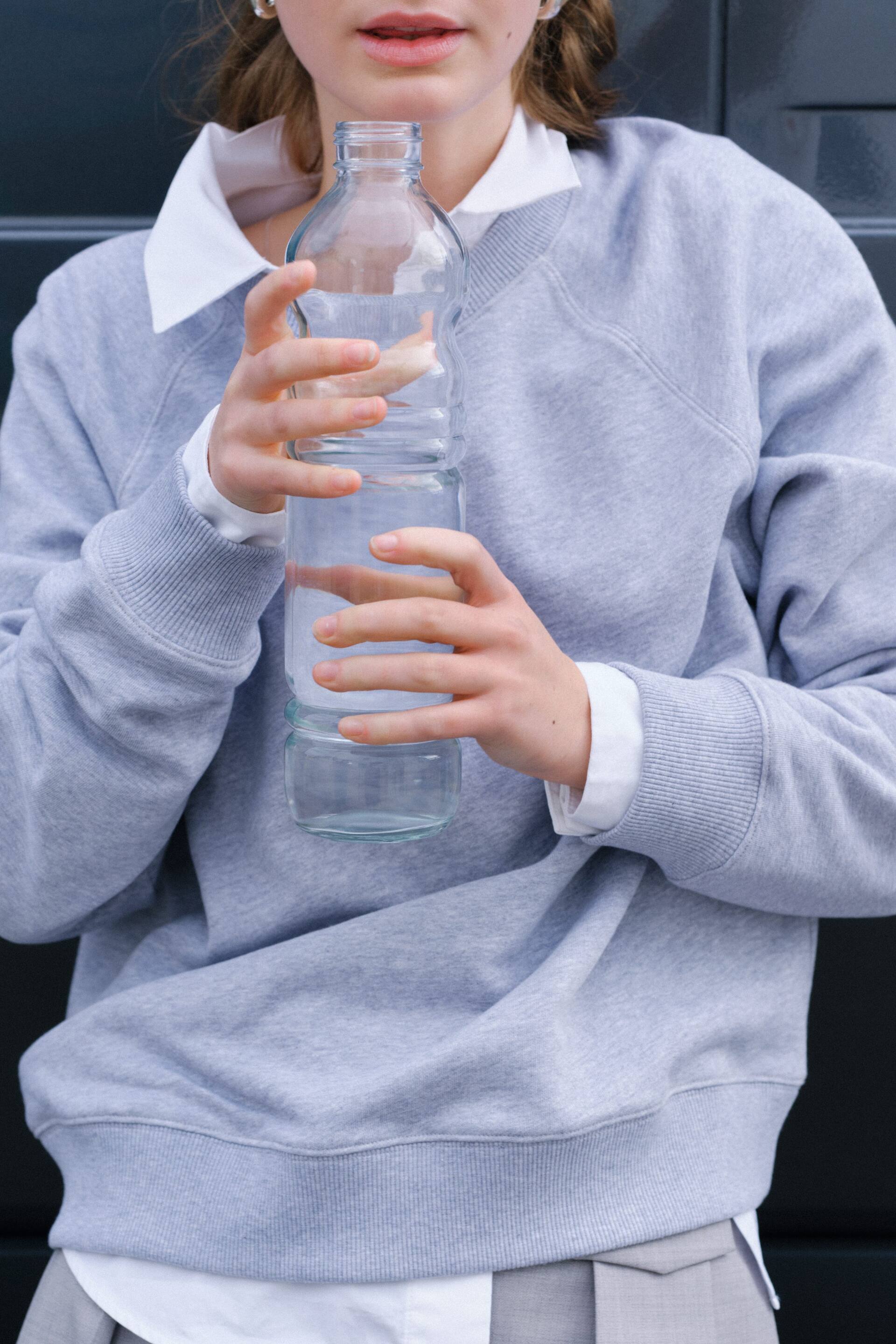 Agrandir l'image: Un sweat-shirt gris clair est doté d'un col rond côtelé avec un insert en V, de manches raglan, de poignets côtelés et d'un ourlet côtelé. Il est superposé à une chemise blanche à col, visible au niveau du col, des poignets et du bas.