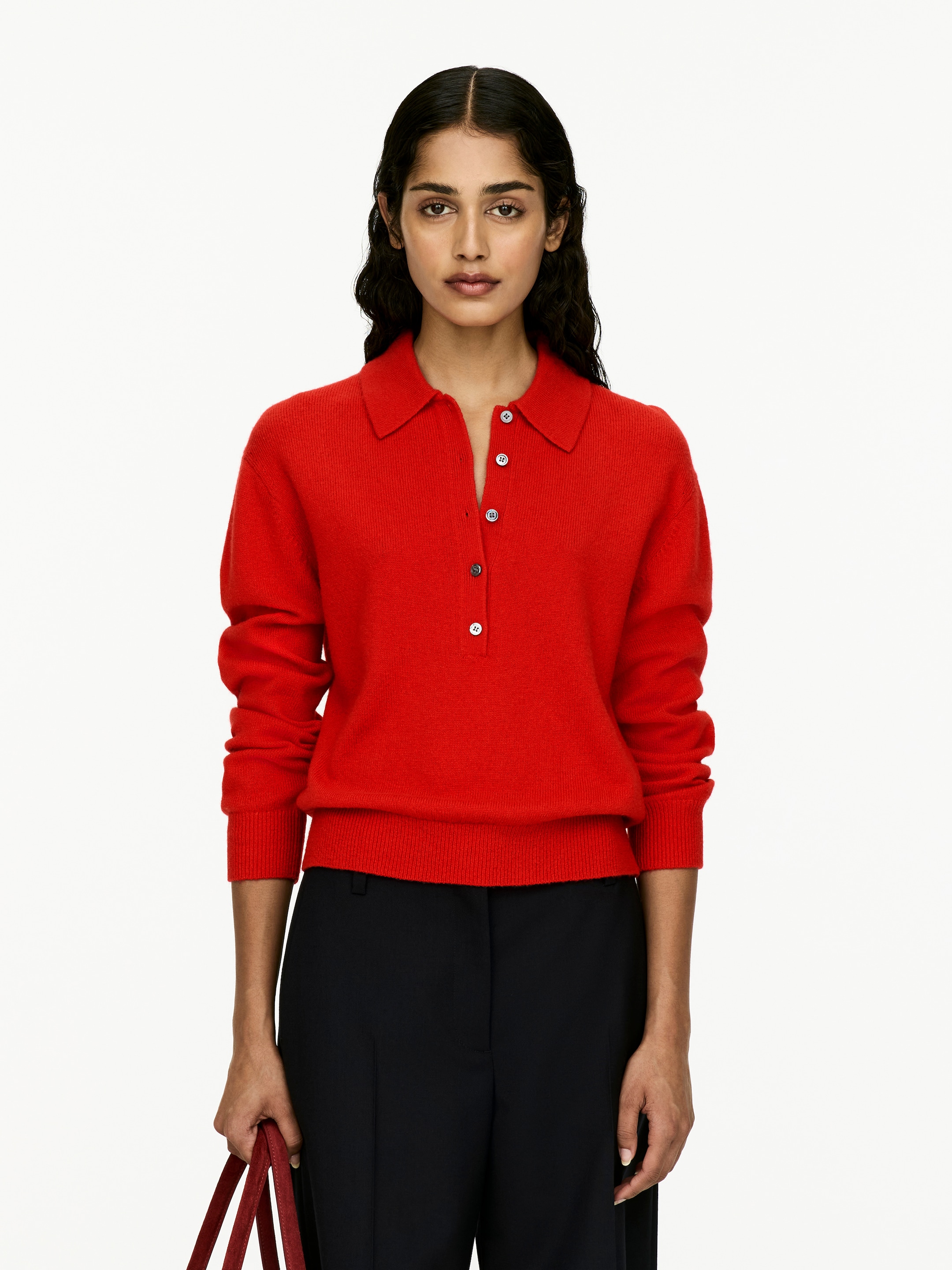 Agrandir l'image: Un pull polo en tricot rouge est présenté de face. Il présente un col polo classique, une patte de boutonnage à quatre boutons, et des poignets et un ourlet côtelés.